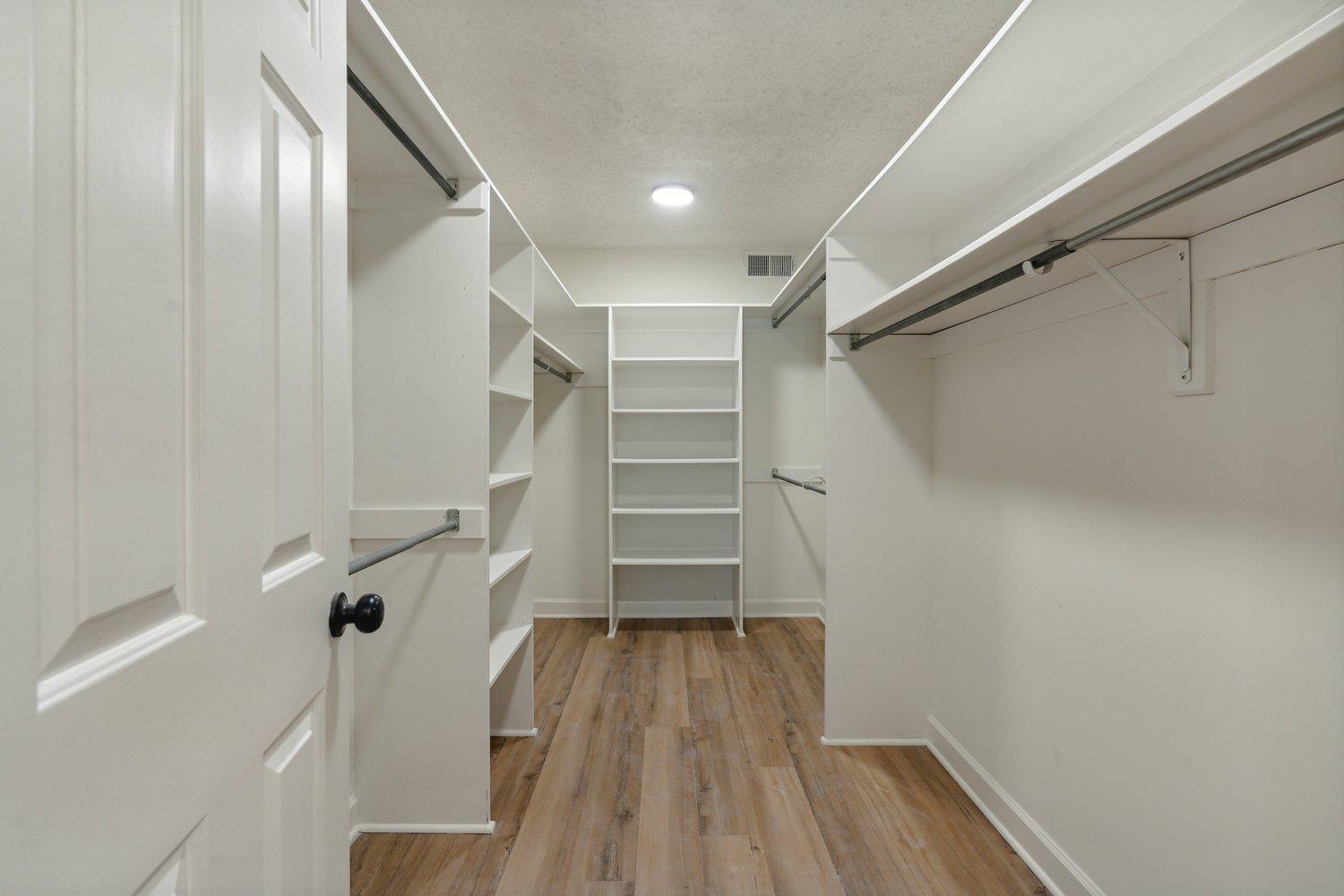 Walk in closet with light hardwood / wood-style floors