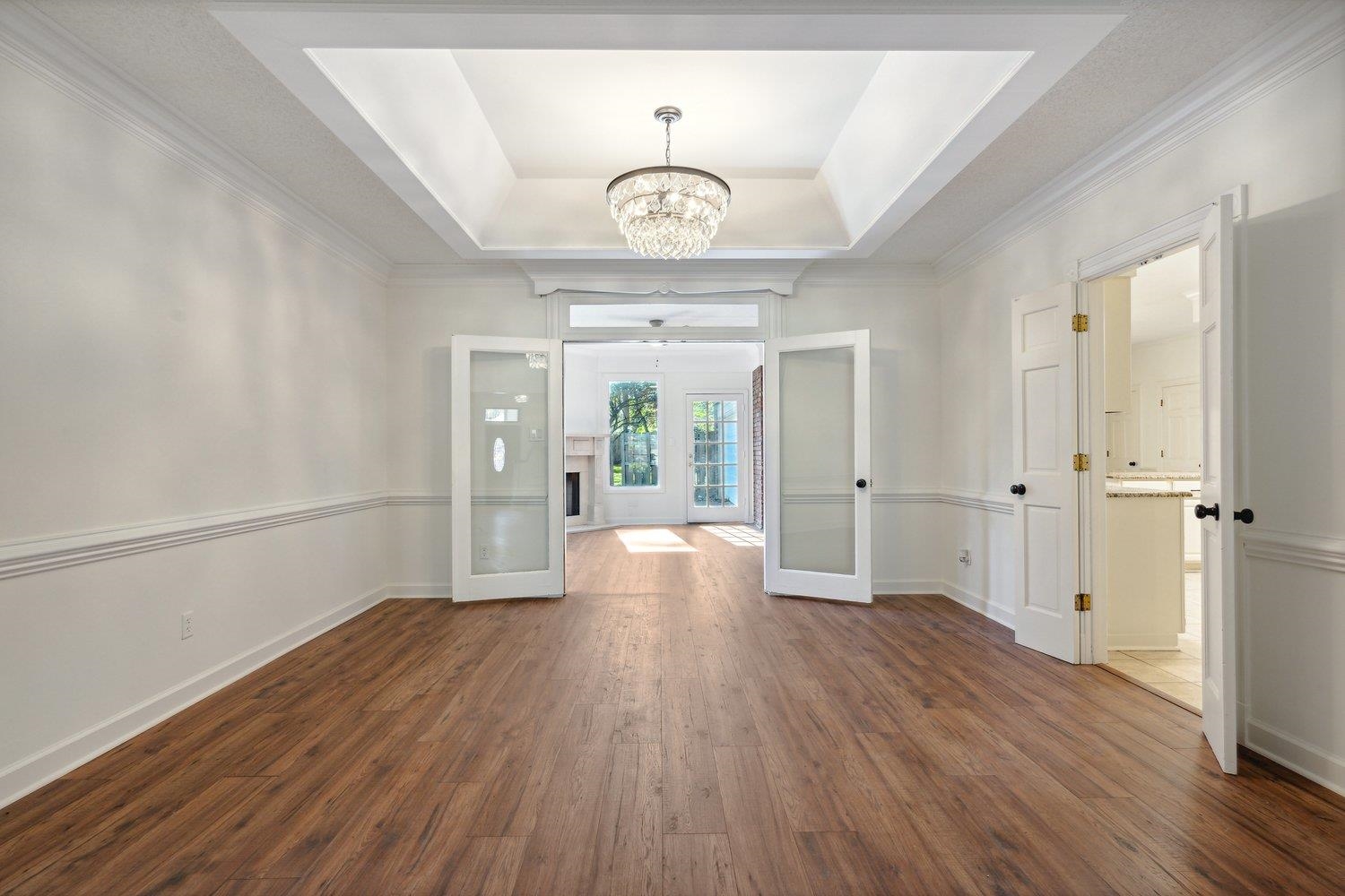 Foyer featuring ornamental molding, a raised ceiling, a notable chandelier, dark wood-type flooring, and french doors