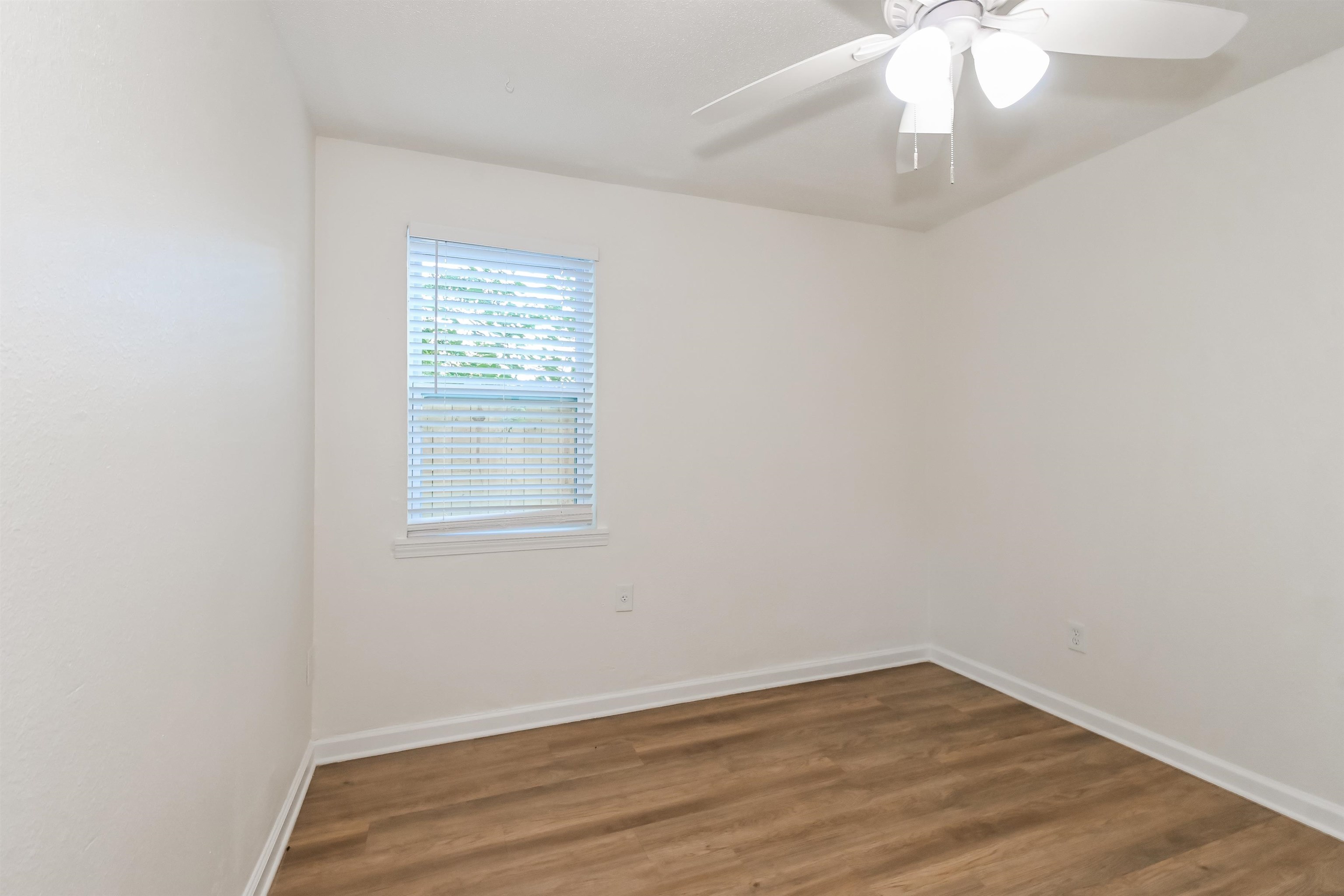 Empty room featuring dark hardwood / wood-style flooring and ceiling fan