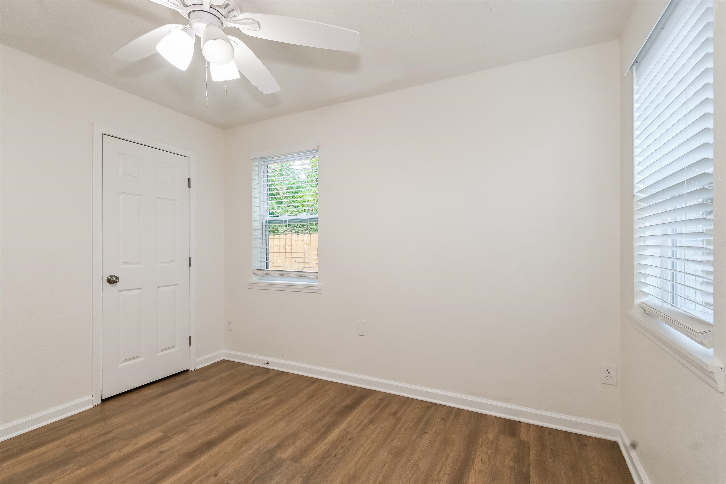 Empty room featuring dark wood-type flooring and ceiling fan