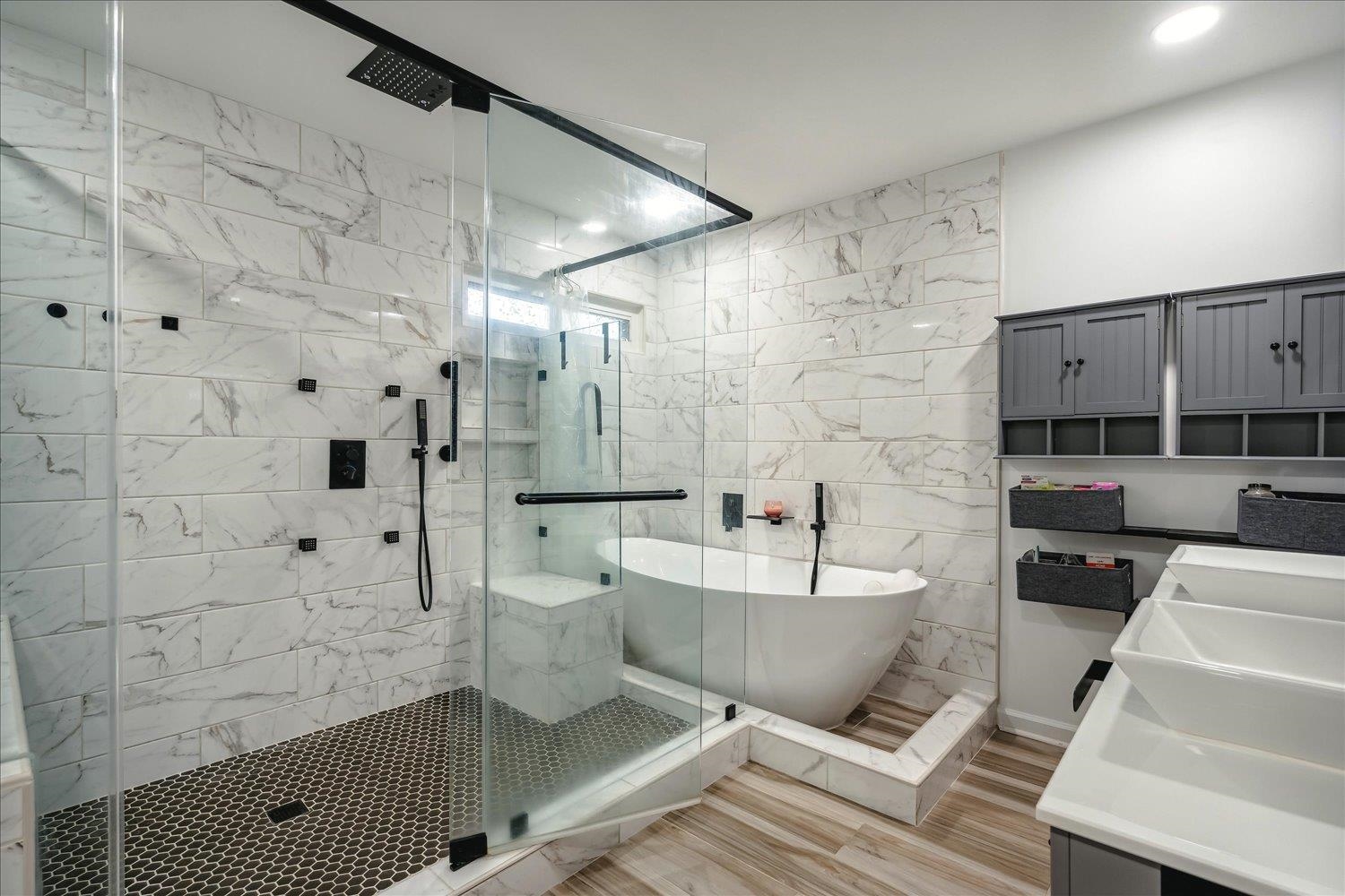 Bathroom with tile walls, vanity, shower with separate bathtub, and hardwood / wood-style flooring