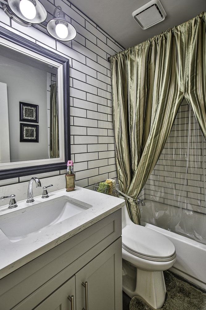 Full bathroom with vanity, toilet, tile walls, and shower / tub combo