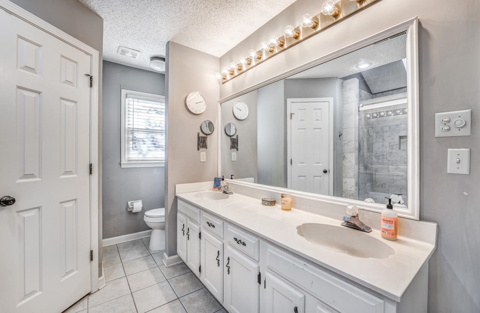 Bathroom with a tile shower, tile patterned flooring, a textured ceiling, toilet, and vanity