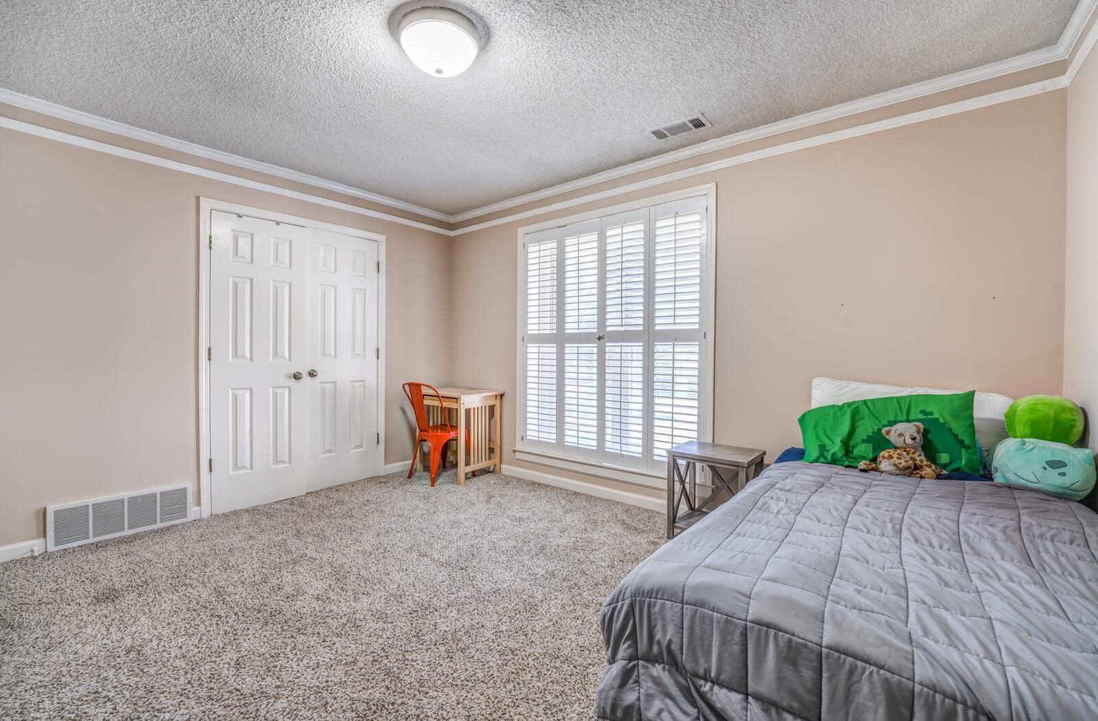 Bedroom featuring a closet, carpet, crown molding, and a textured ceiling