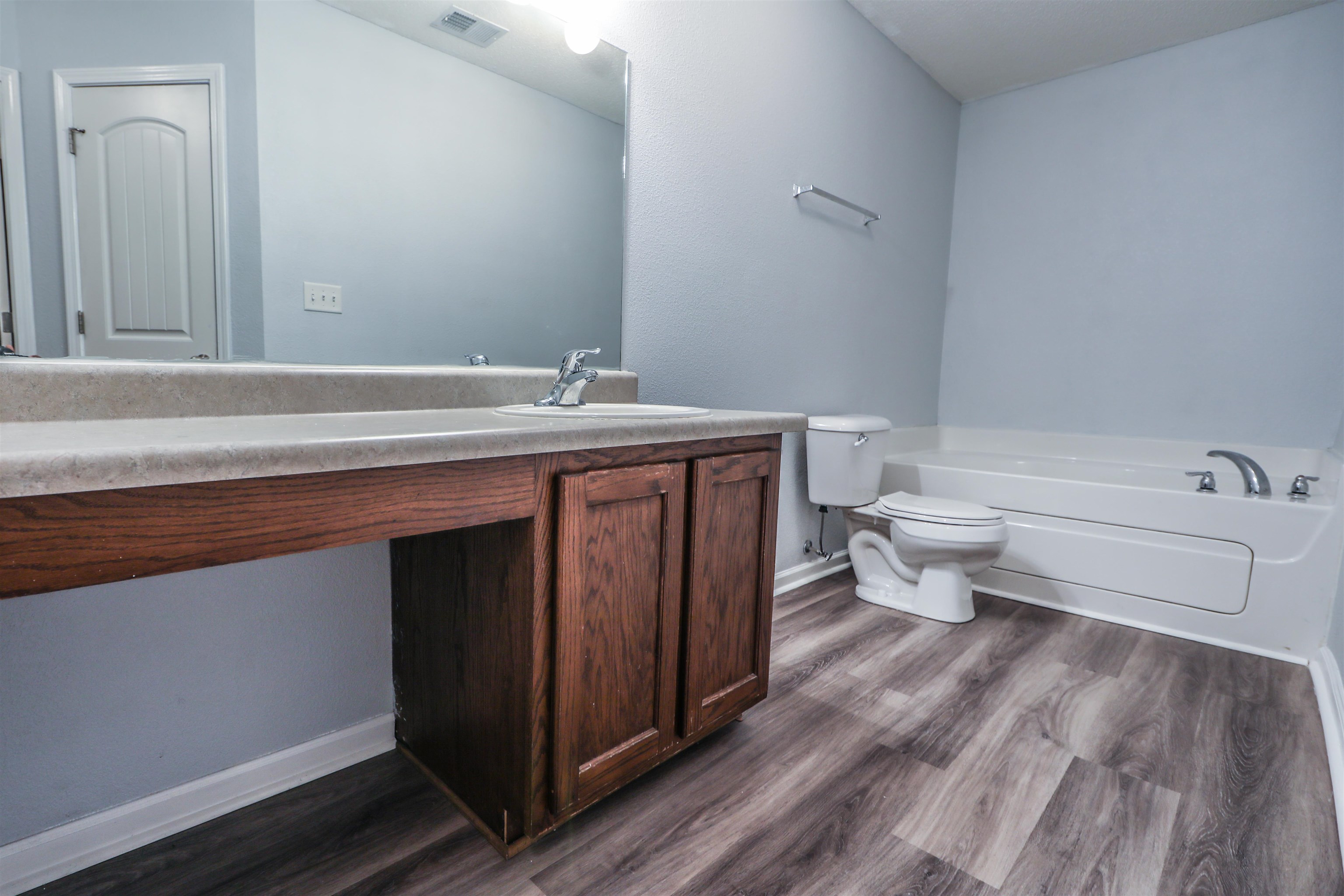 Bathroom with a tub, toilet, vanity, and hardwood / wood-style flooring