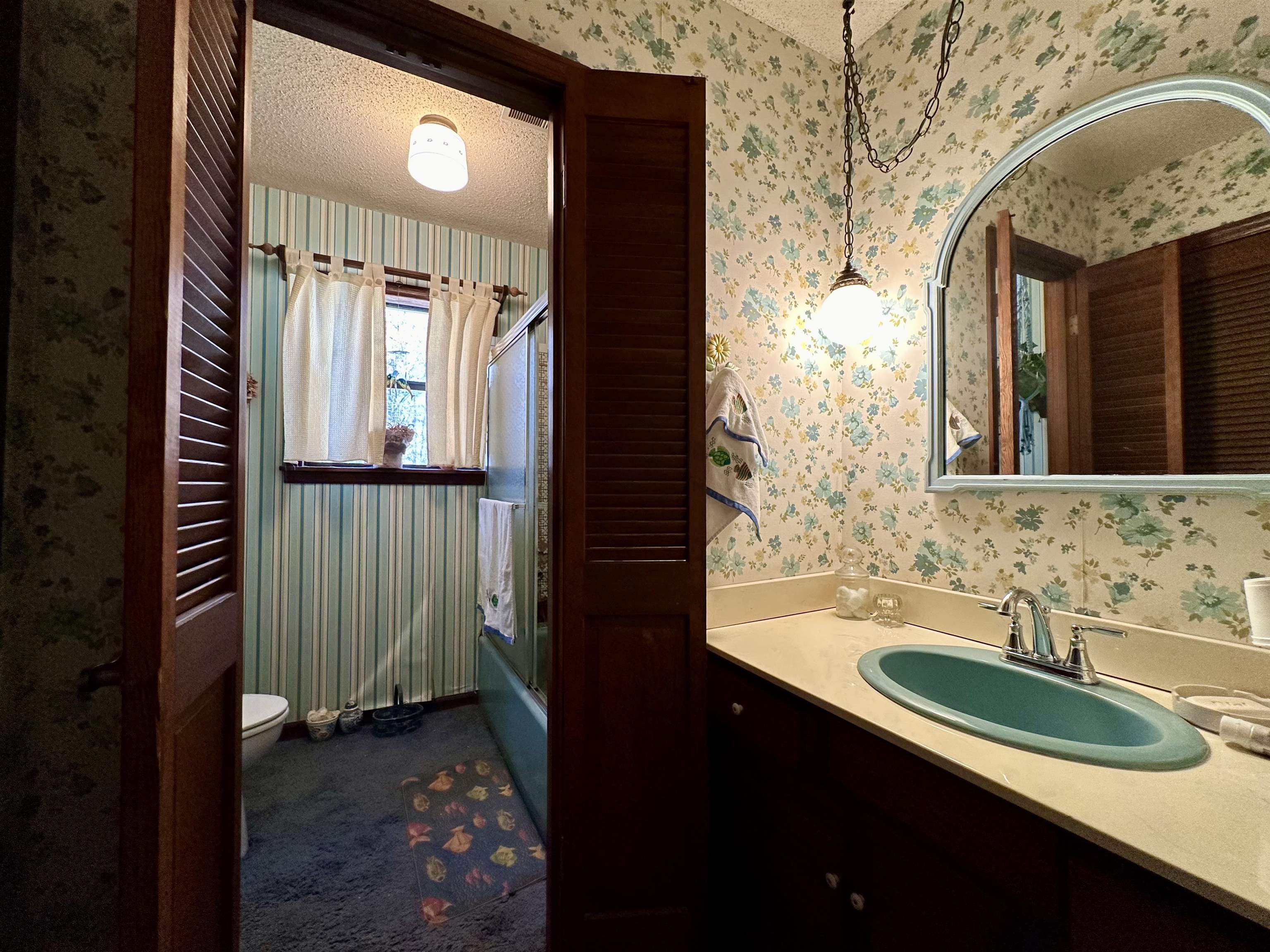 Full bathroom with vanity, a textured ceiling, toilet, and bath / shower combo with glass door