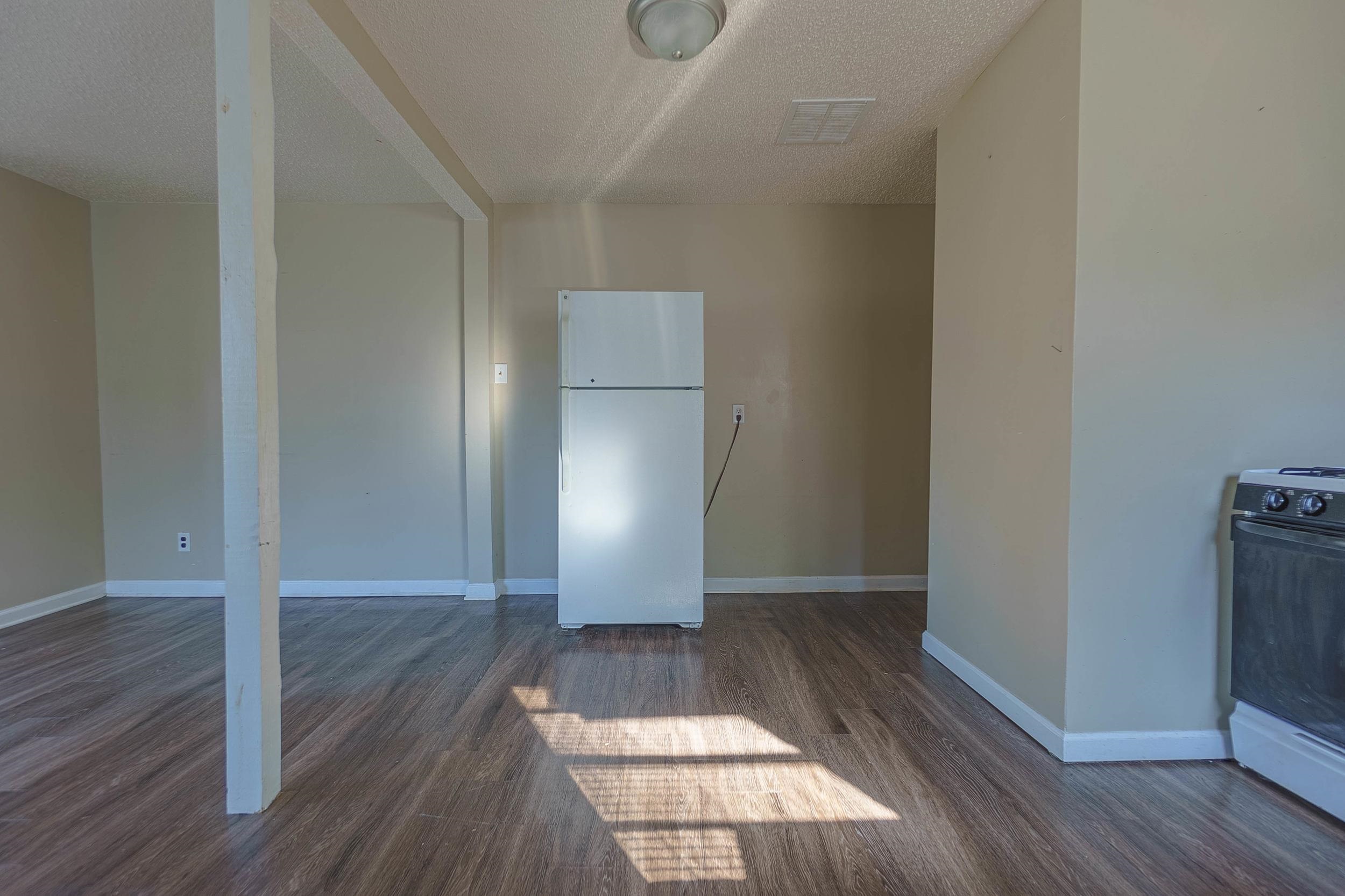 Unfurnished living room featuring dark hardwood / wood-style flooring and a textured ceiling