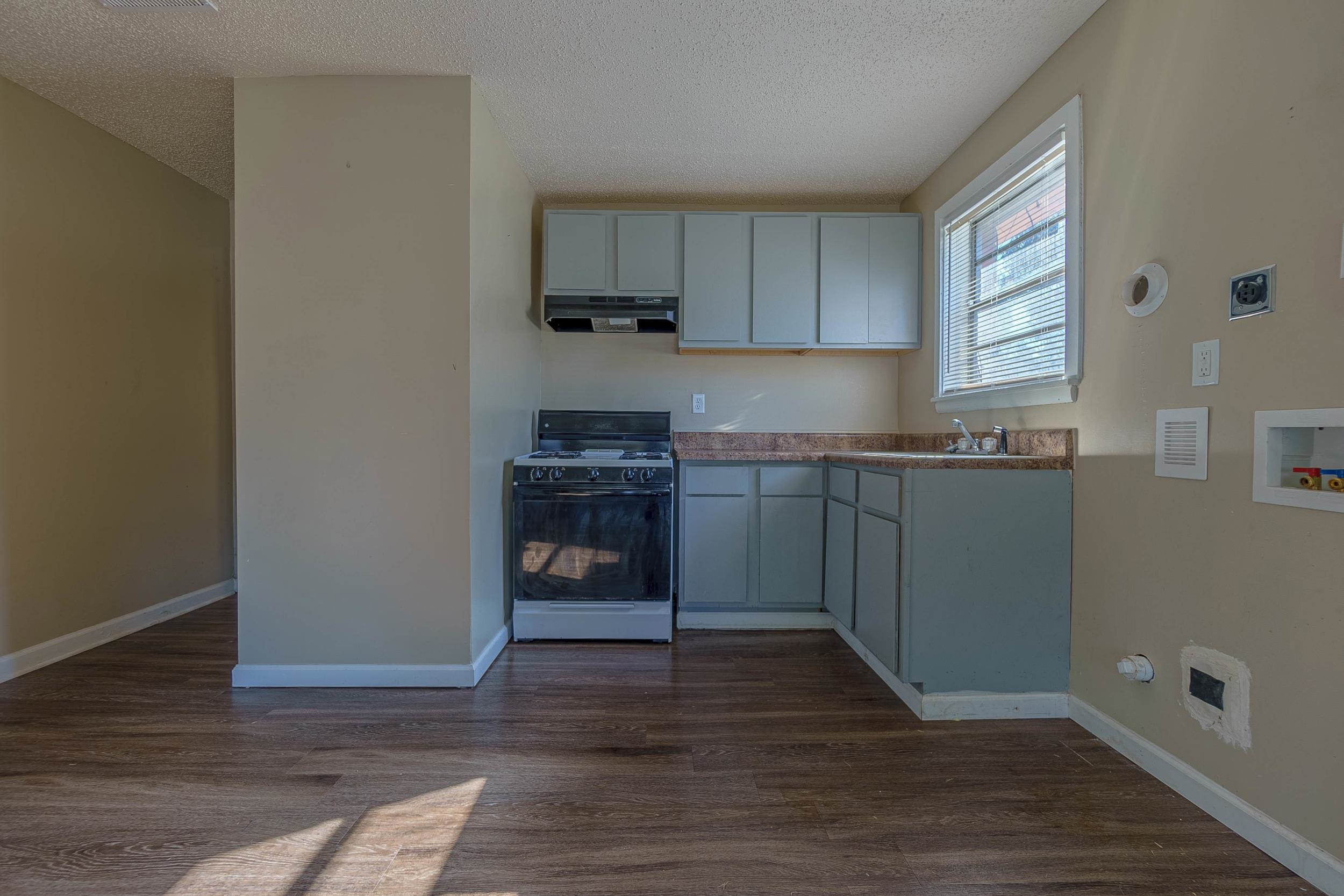 Kitchen with a textured ceiling, range with gas cooktop, dark hardwood / wood-style floors, and sink