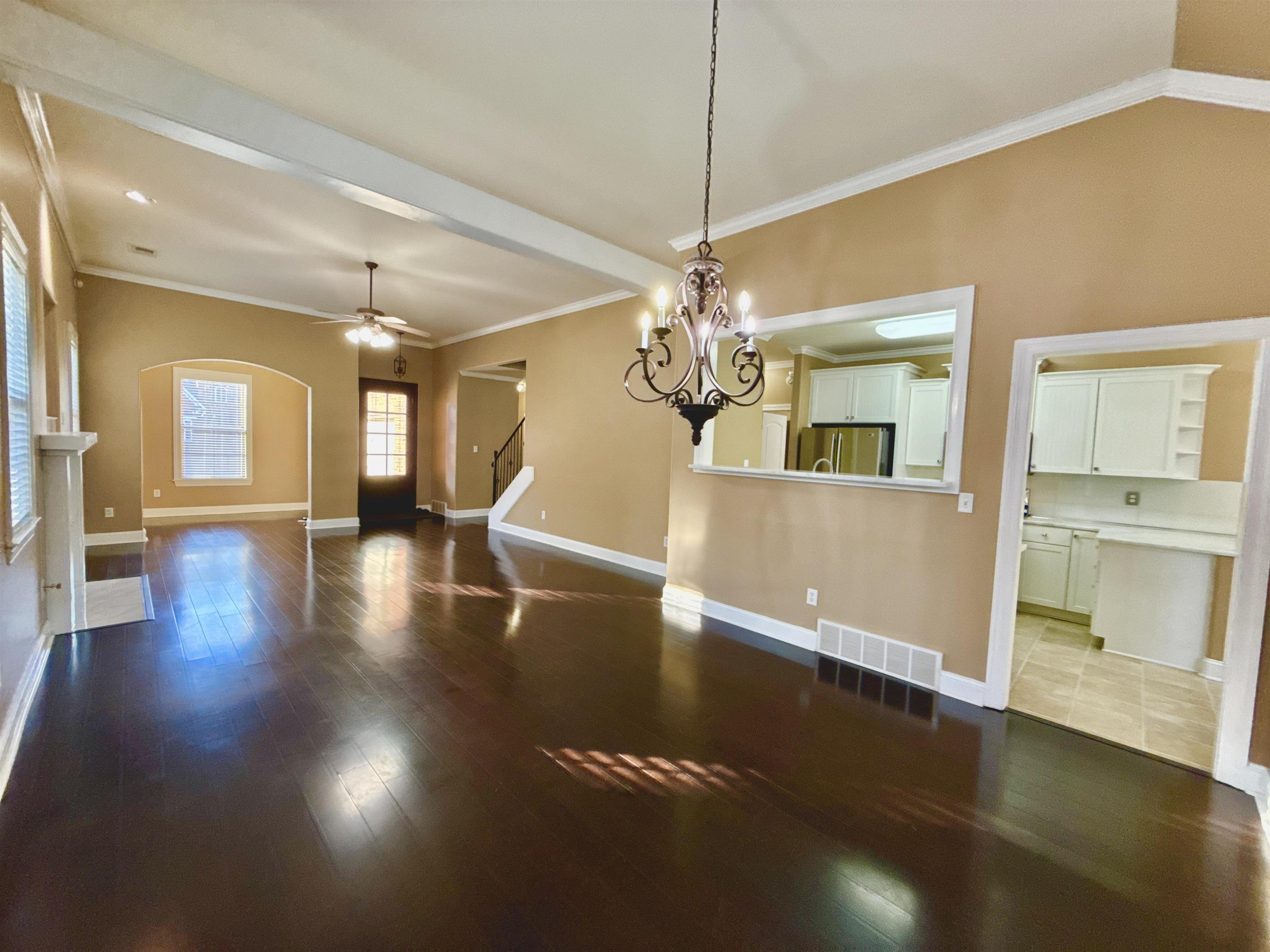 Unfurnished dining area featuring crown molding, hardwood / wood-style floors, and ceiling fan with notable chandelier