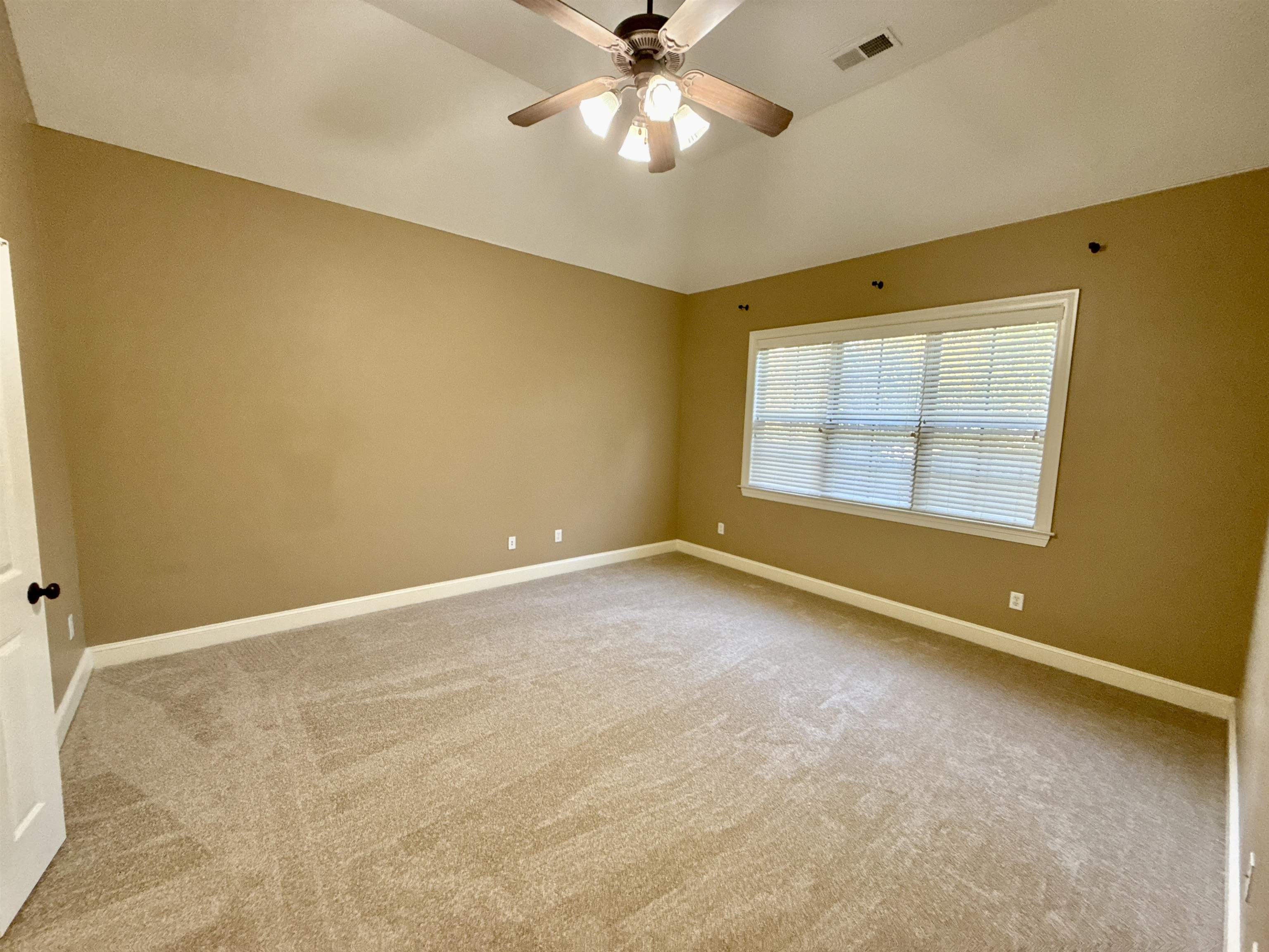 Empty room with light colored carpet and ceiling fan