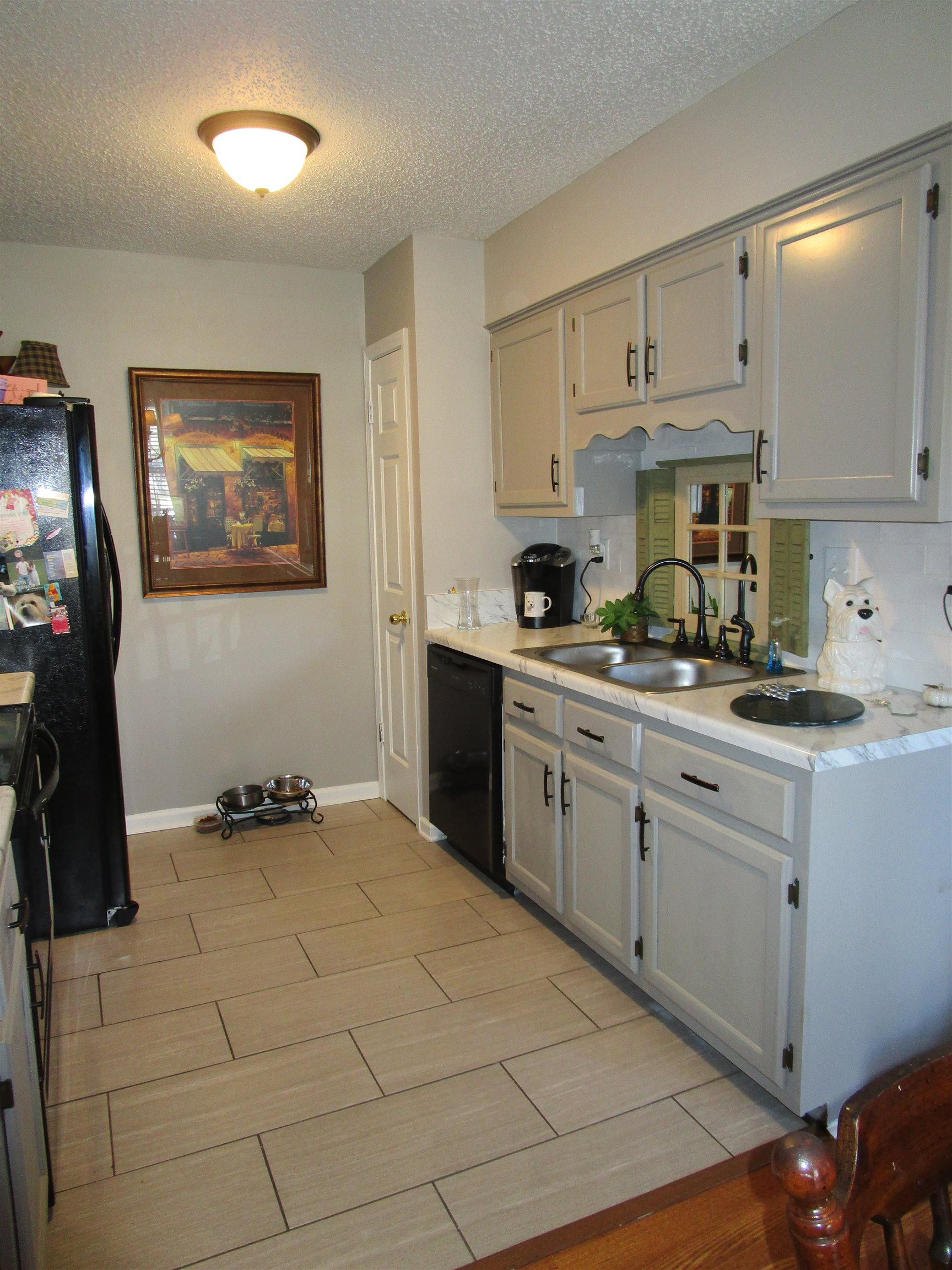 Kitchen featuring a textured ceiling, sink, and black appliances   Nice Pantry in corner