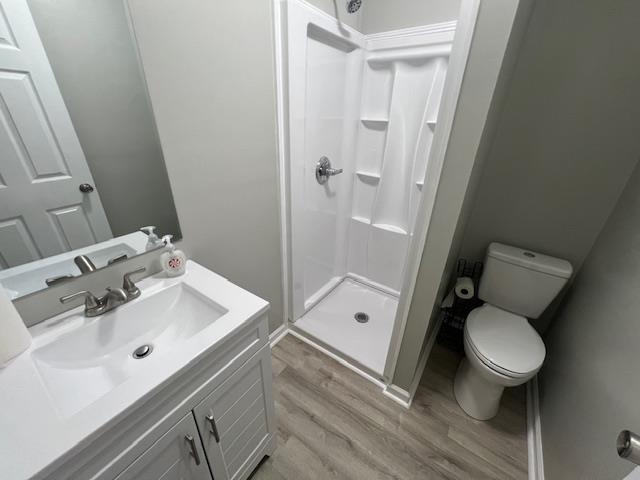 Bathroom featuring toilet, vanity, wood-type flooring, and walk in shower