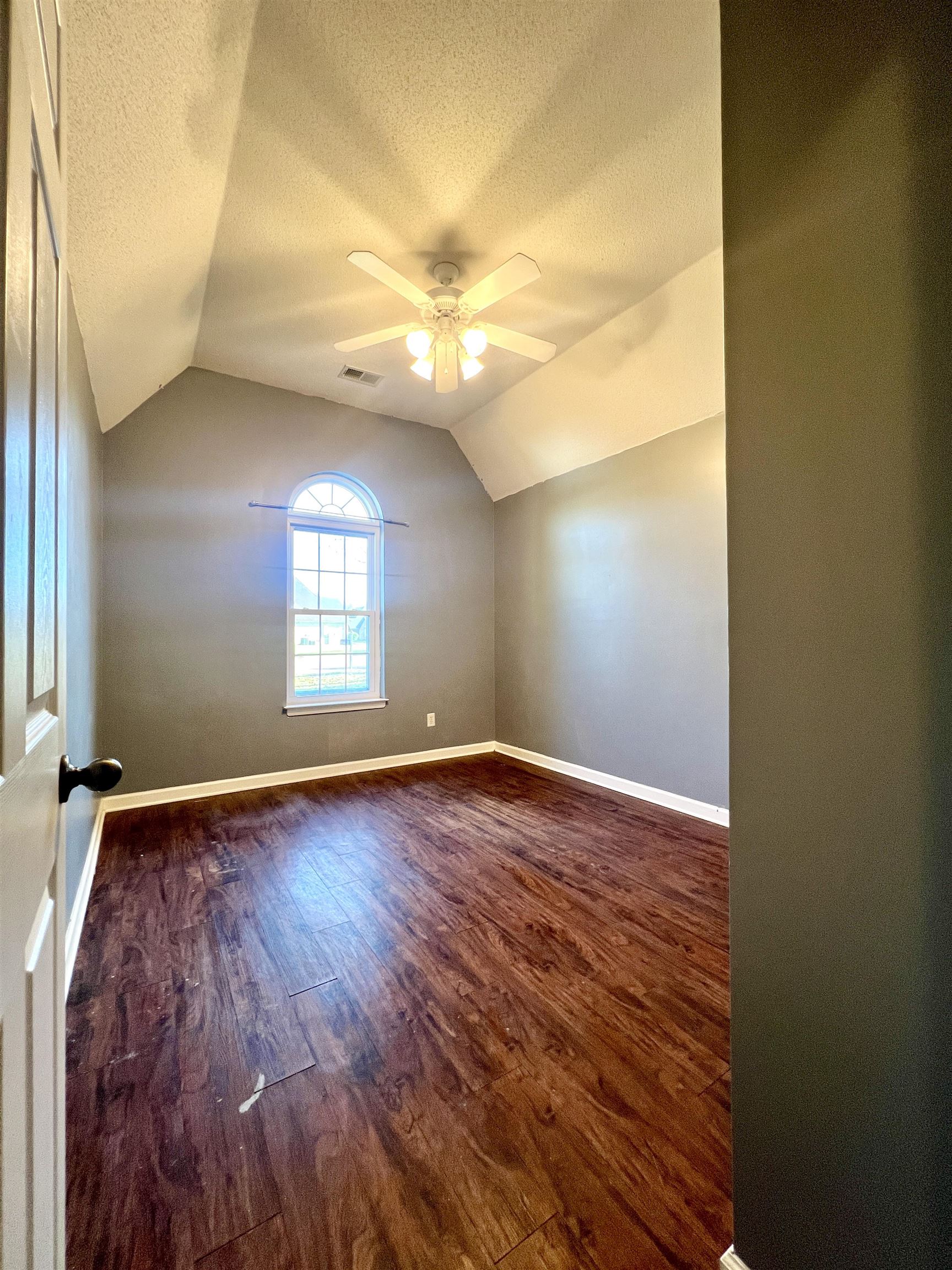 Bonus room featuring lofted ceiling, dark hardwood / wood-style flooring, ceiling fan, and a textured ceiling