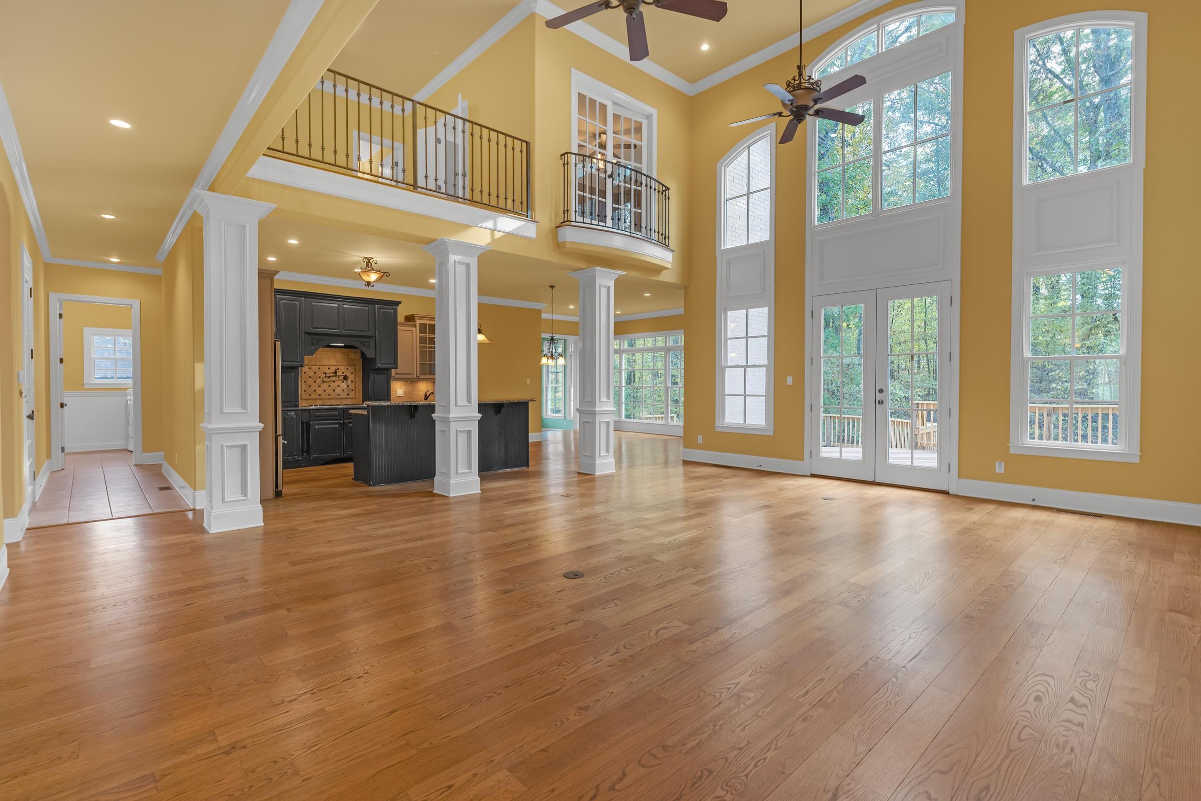 2 story great room open to kitchen and hearth room featuring a wall of windows overlooking the back deck and wooded backyard