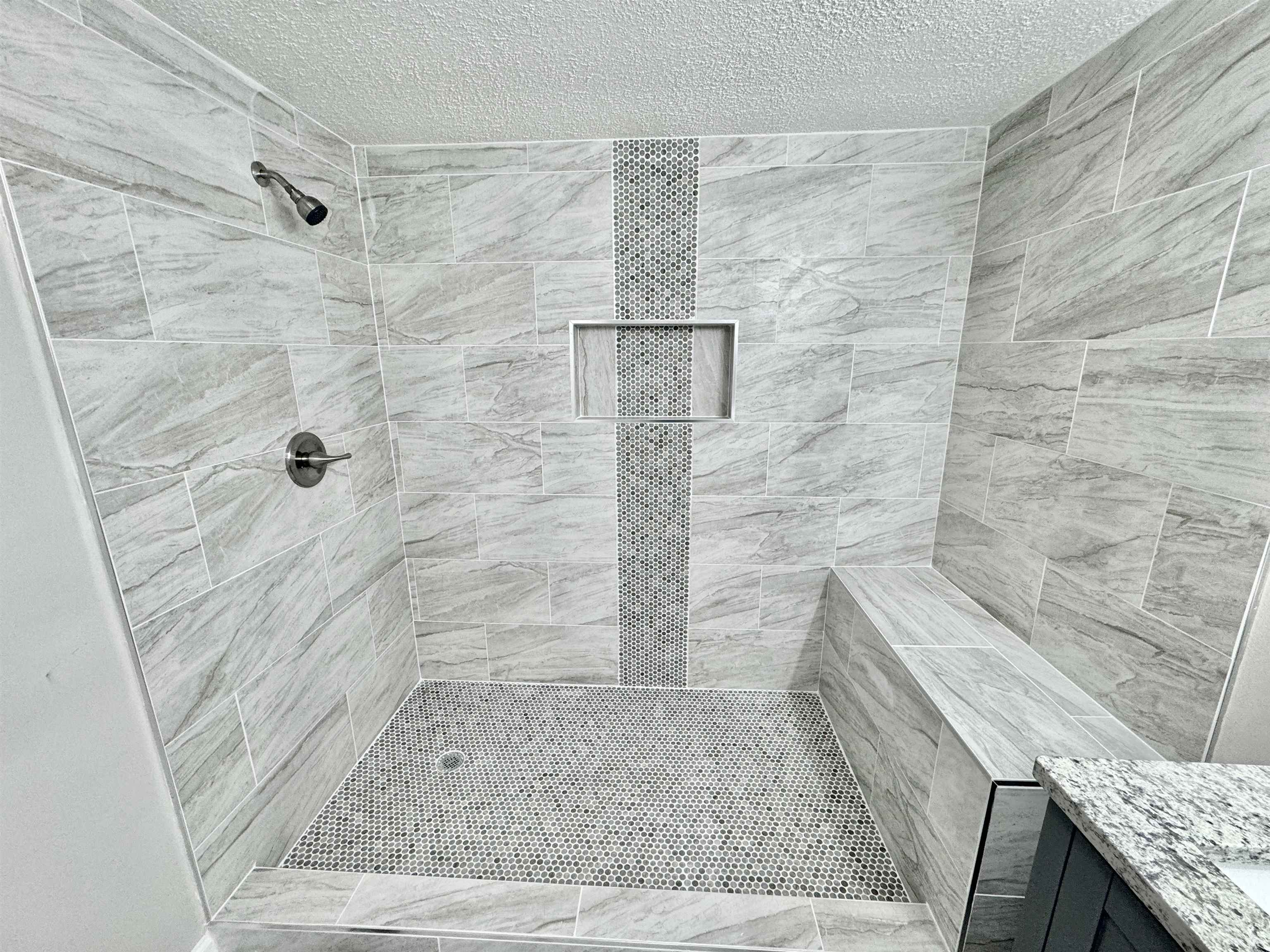 Bathroom featuring tiled shower and a textured ceiling