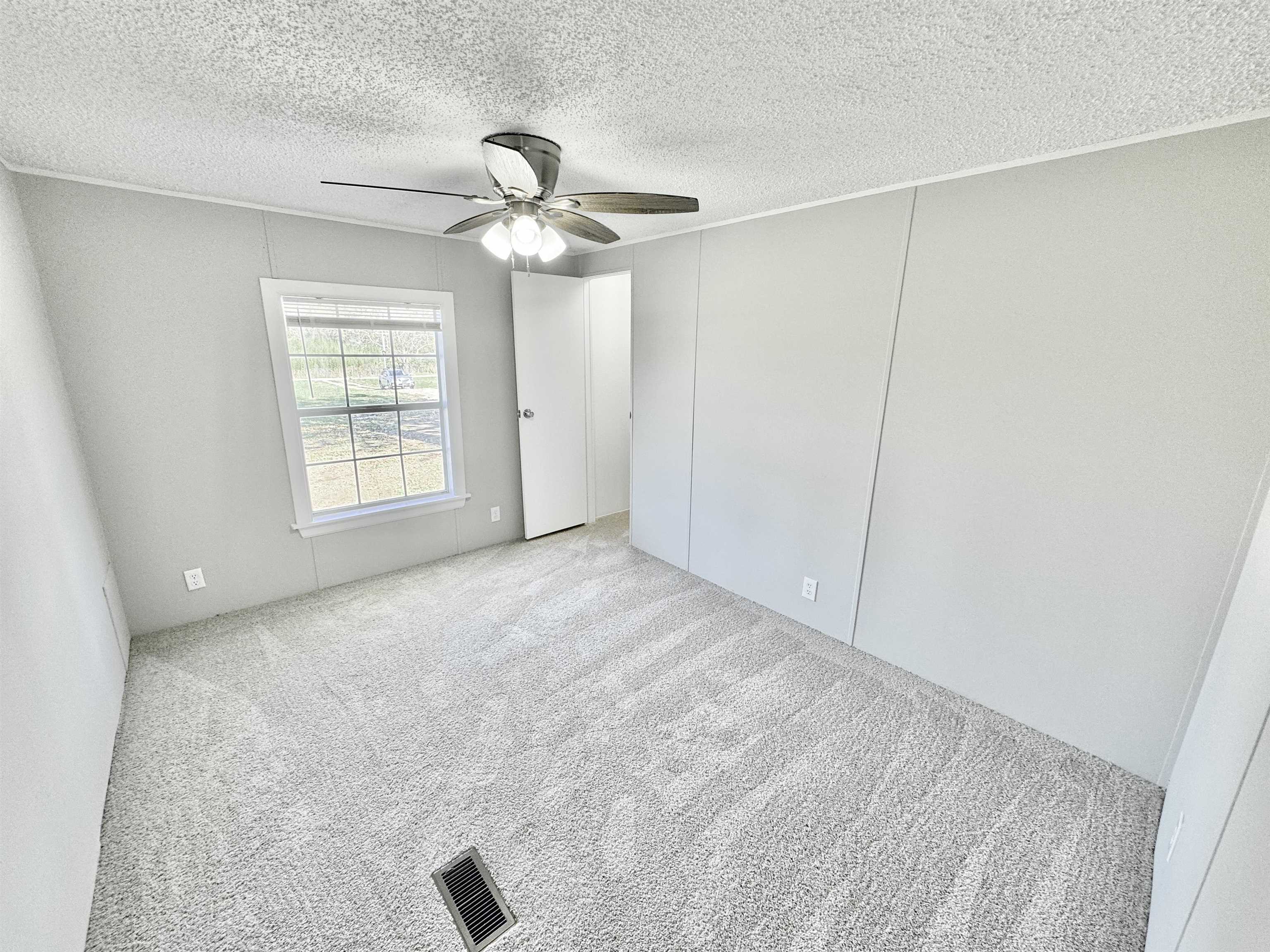 Spare room with a textured ceiling, light colored carpet, and ceiling fan