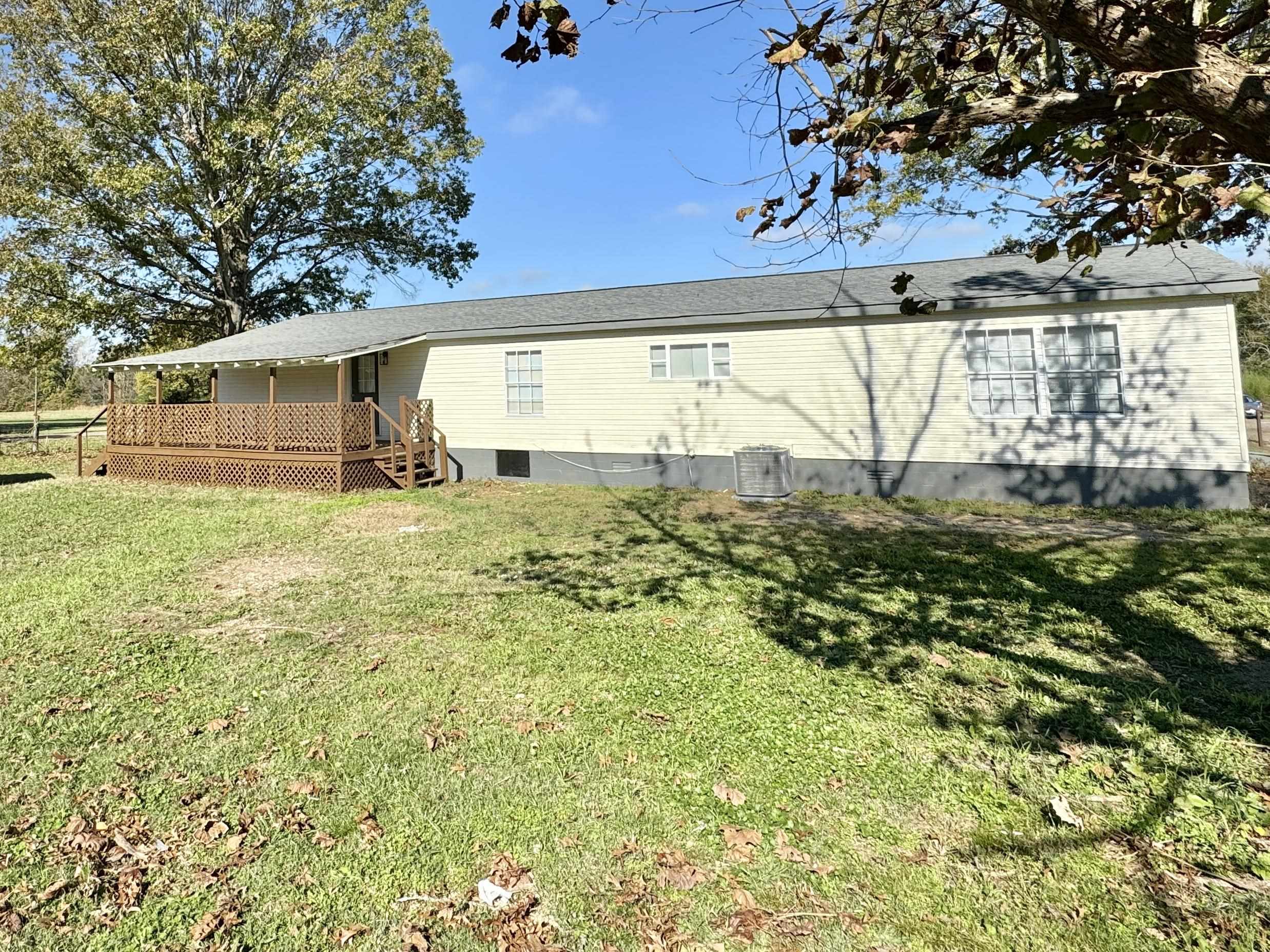 Back of house with a lawn and a wooden deck