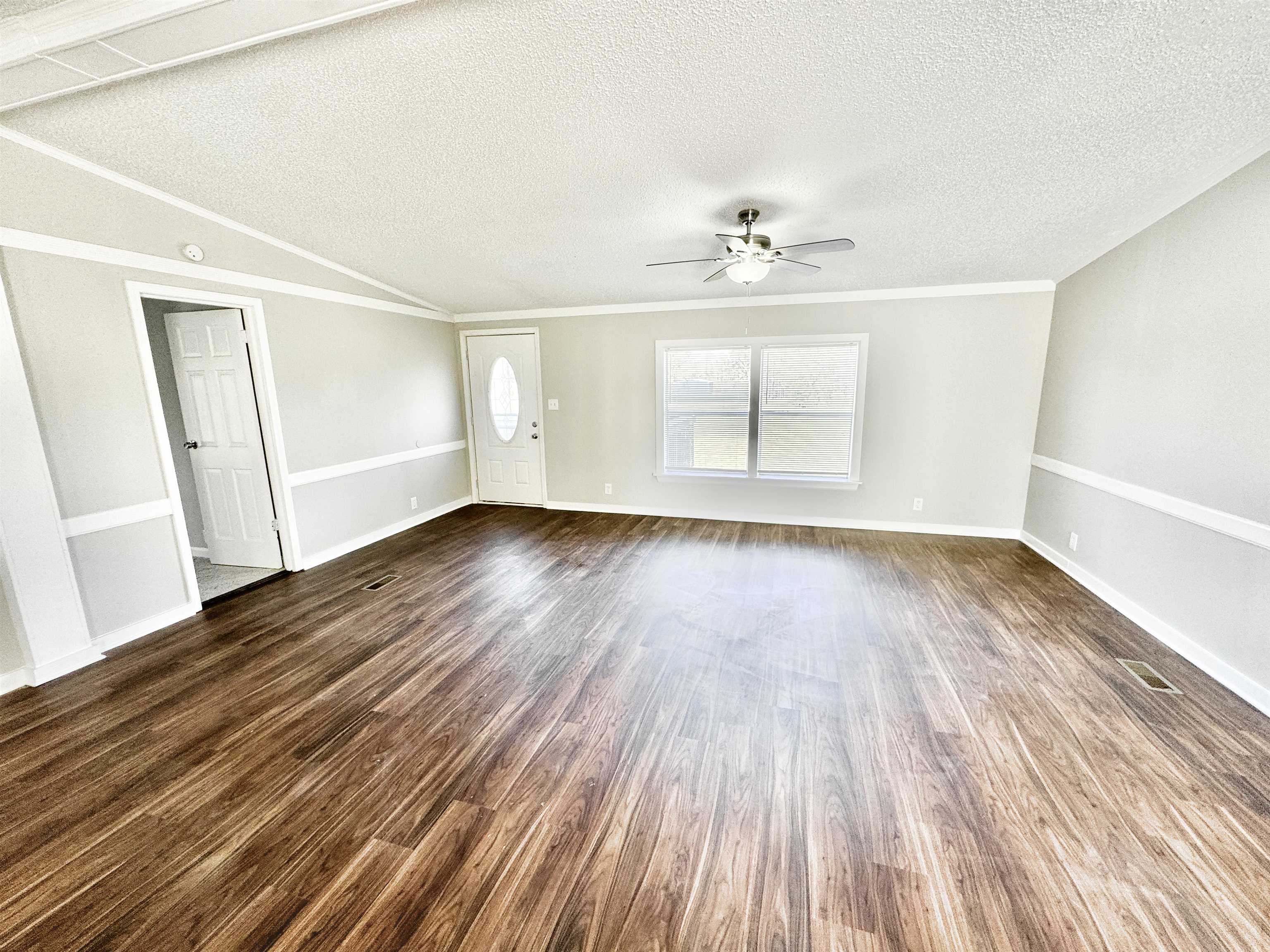 Spare room featuring ceiling fan, dark wood-type flooring, a textured ceiling, and ornamental molding