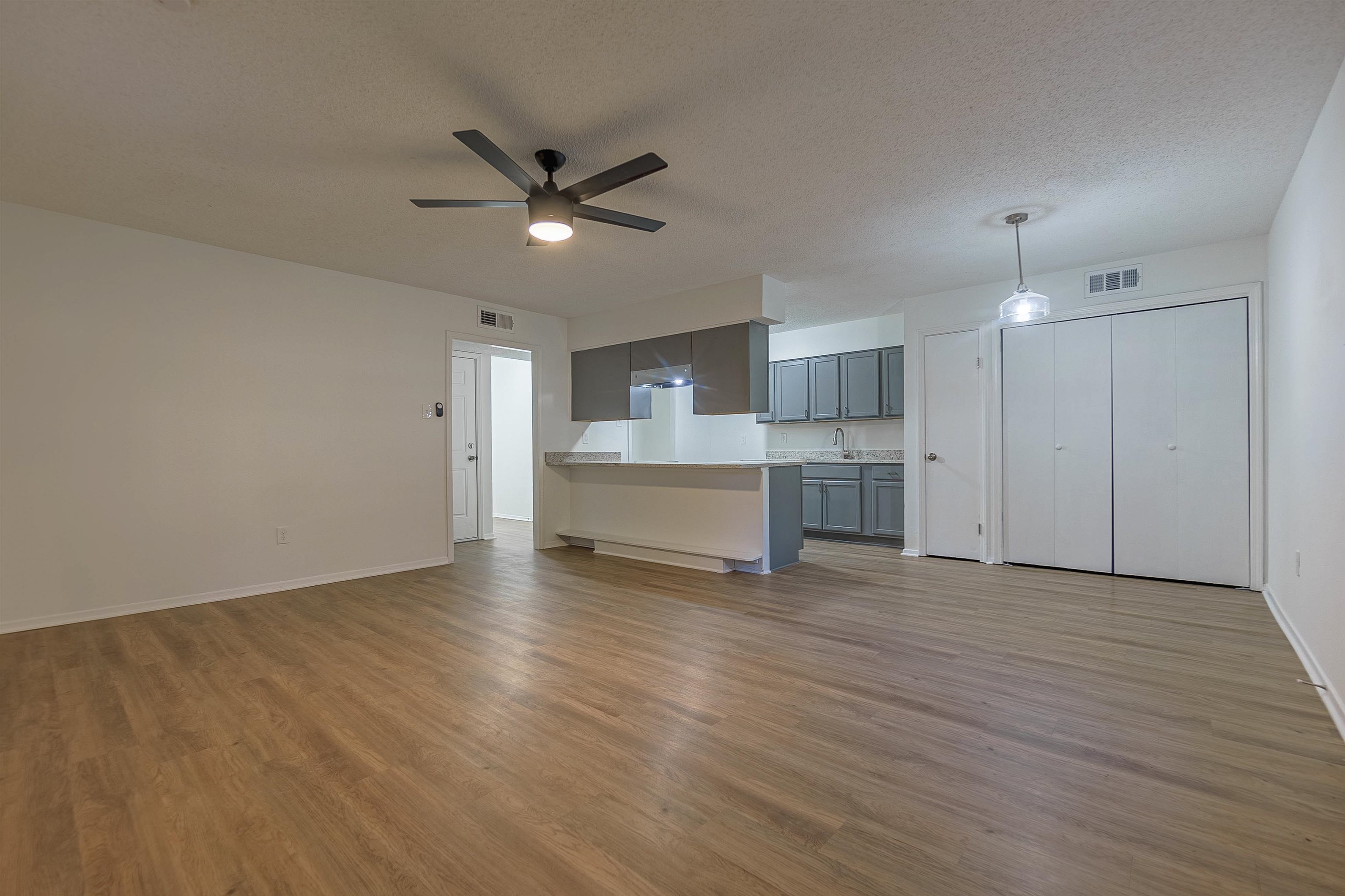 Unfurnished living room featuring ceiling fan, light hardwood / wood-style floors, sink, and a textured ceiling