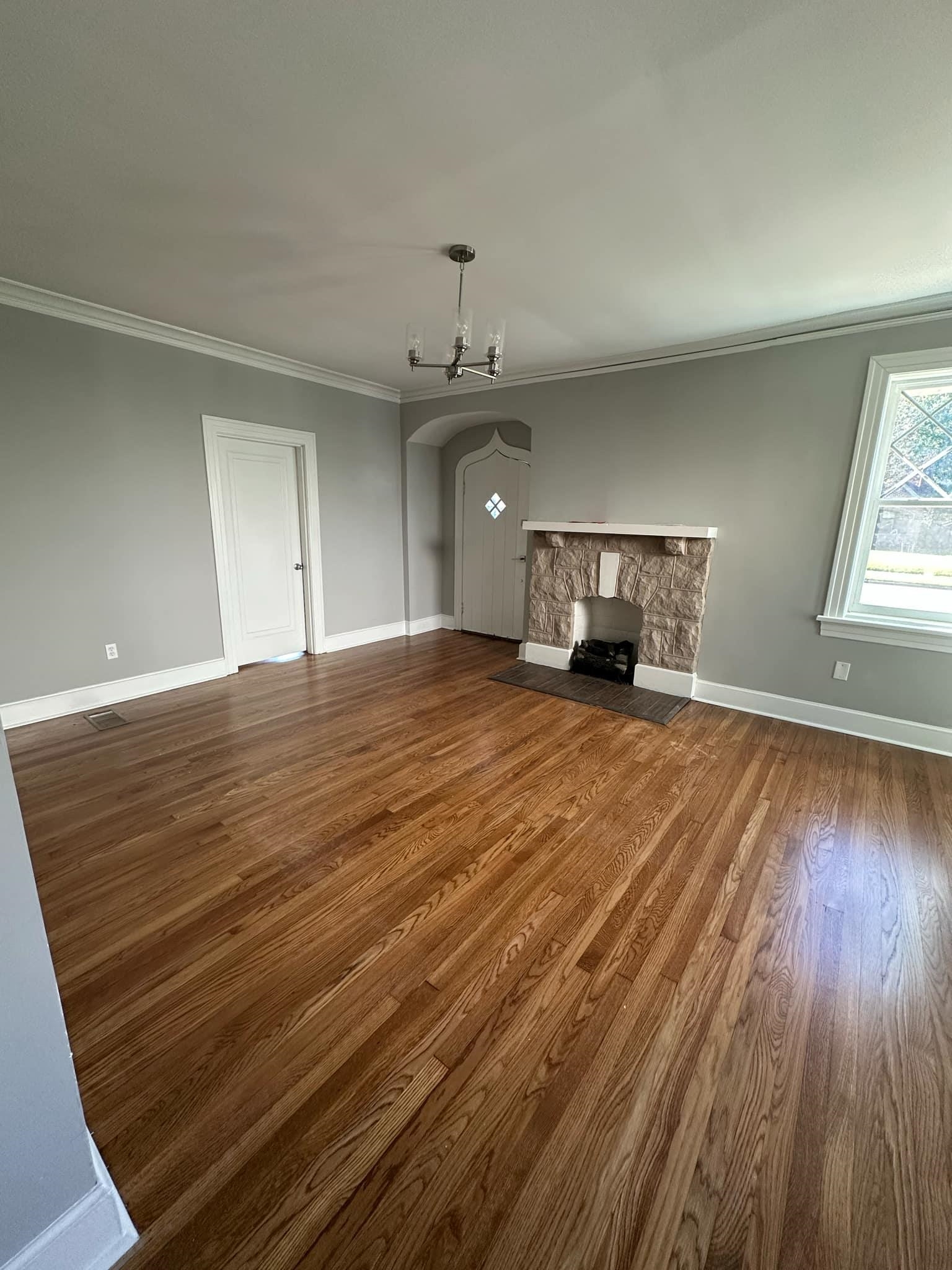 Unfurnished living room featuring a fireplace, crown molding, dark wood-type flooring, and a chandelier