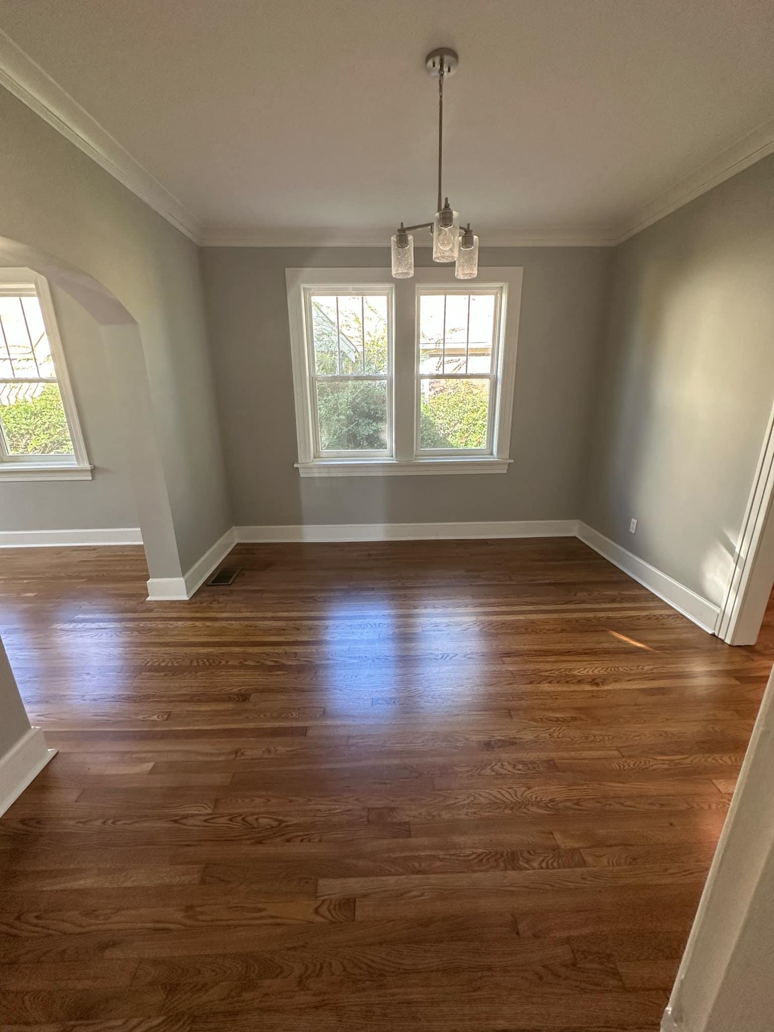 Unfurnished dining area featuring a chandelier, plenty of natural light, and dark wood-type flooring