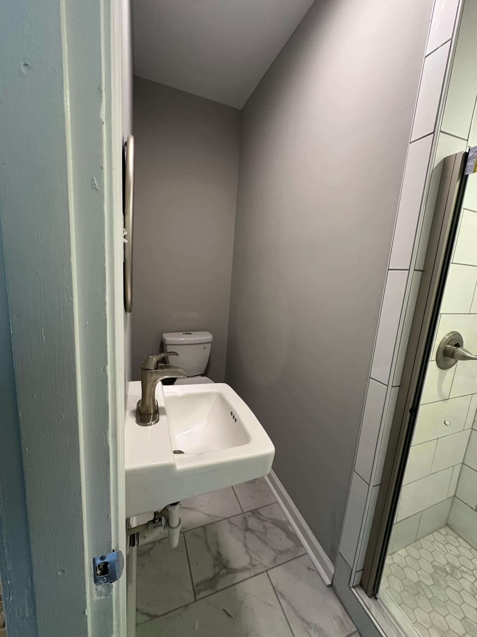 Bathroom featuring walk in shower, sink, and toilet