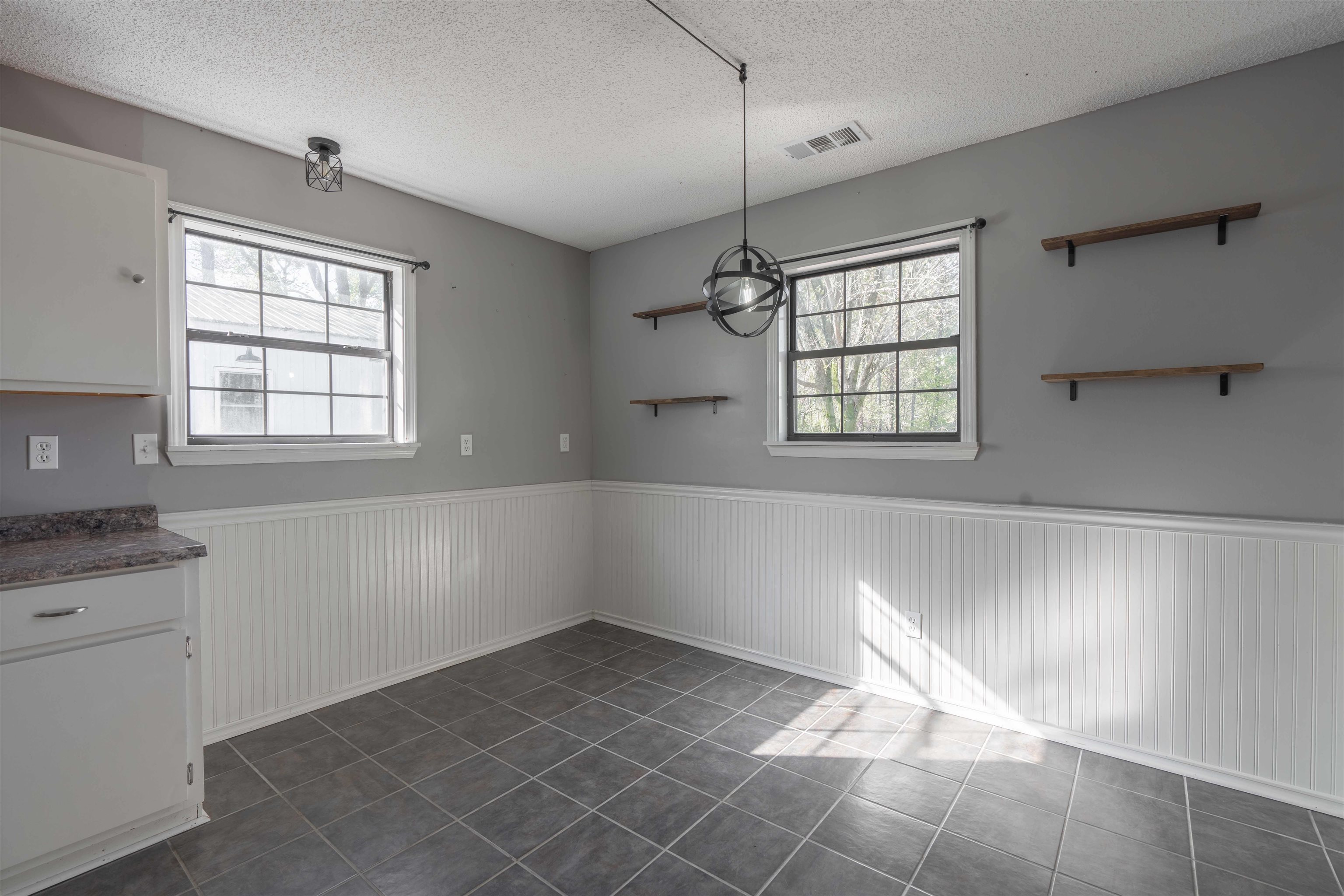 Unfurnished dining area with dark tile patterned flooring and a textured ceiling