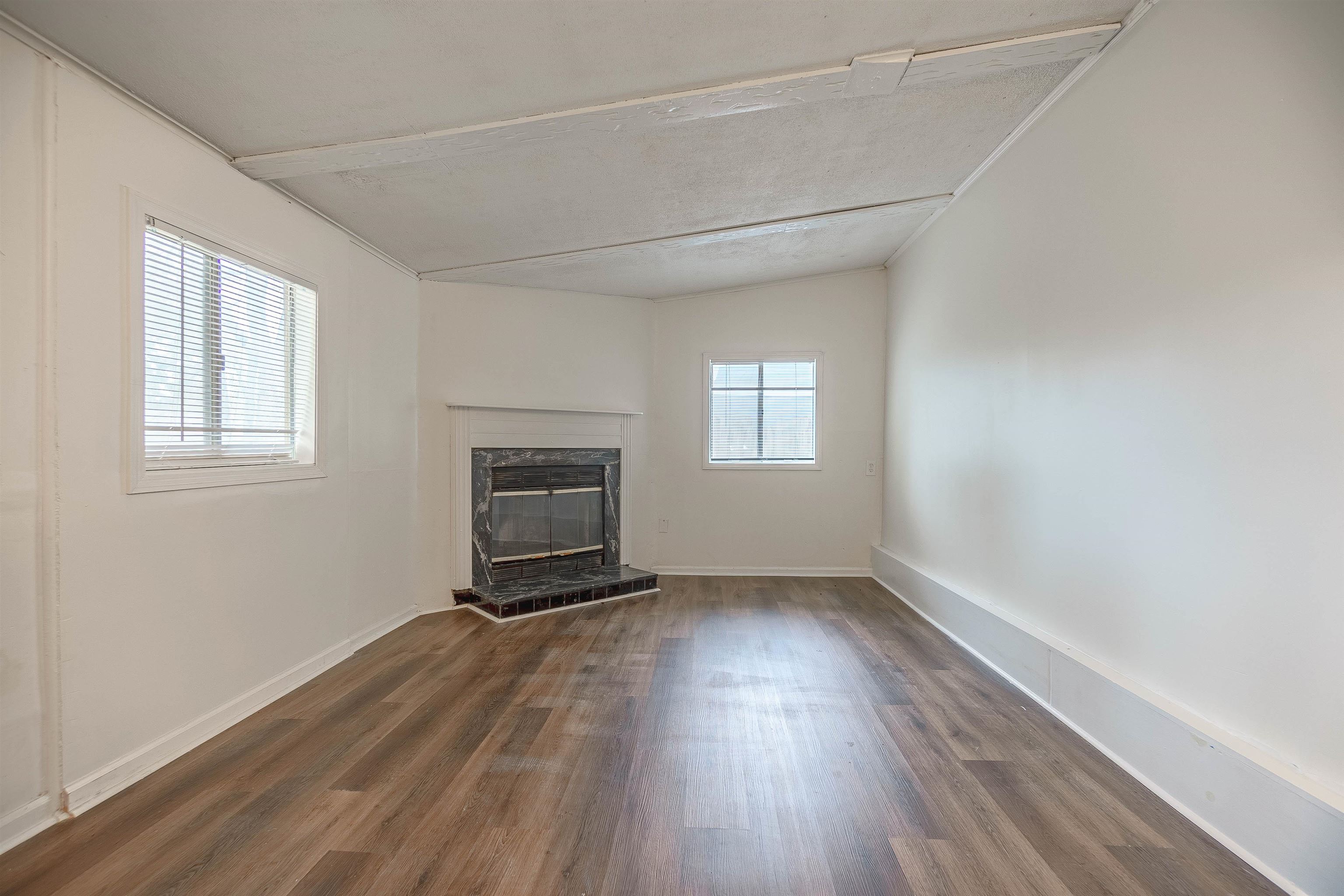 Unfurnished living room featuring plenty of natural light, dark wood-type flooring, and vaulted ceiling