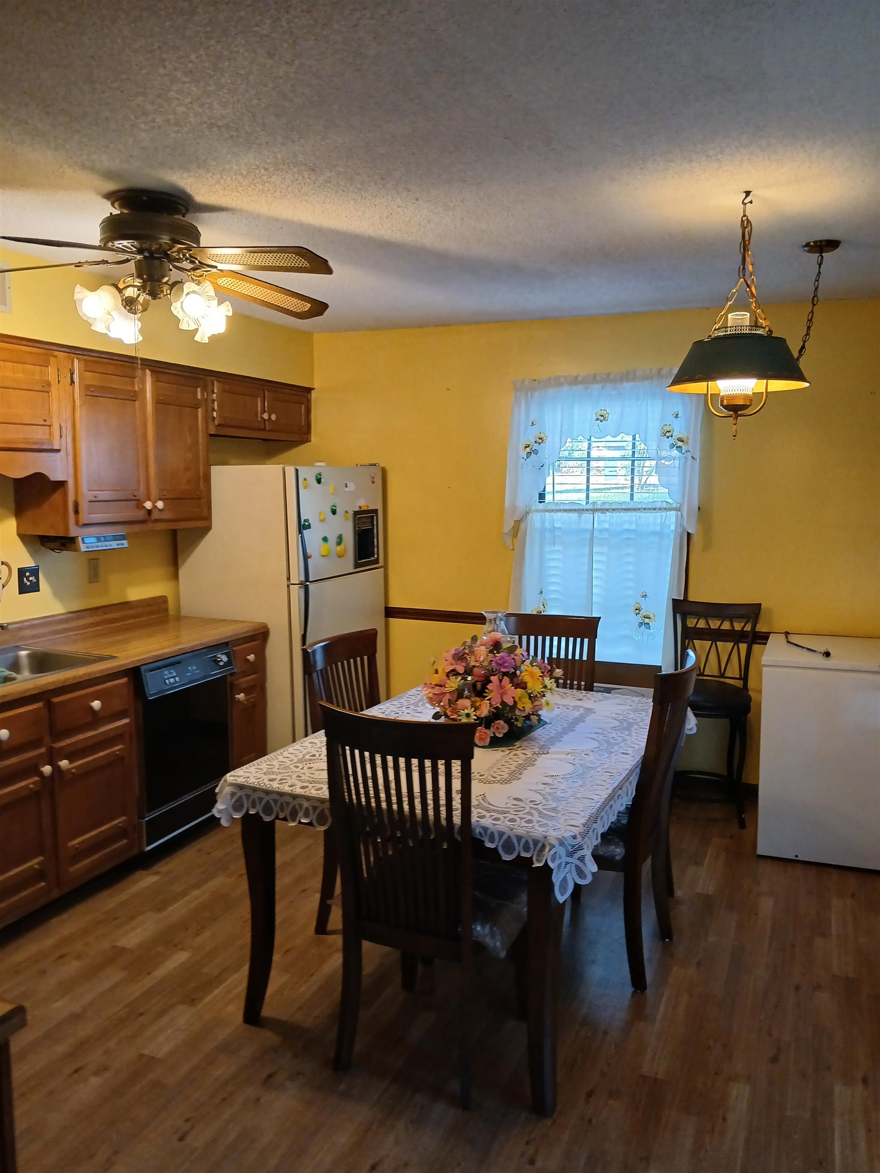 Dining area featuring a textured ceiling, ceiling fan, sink, and dark wood-type flooring