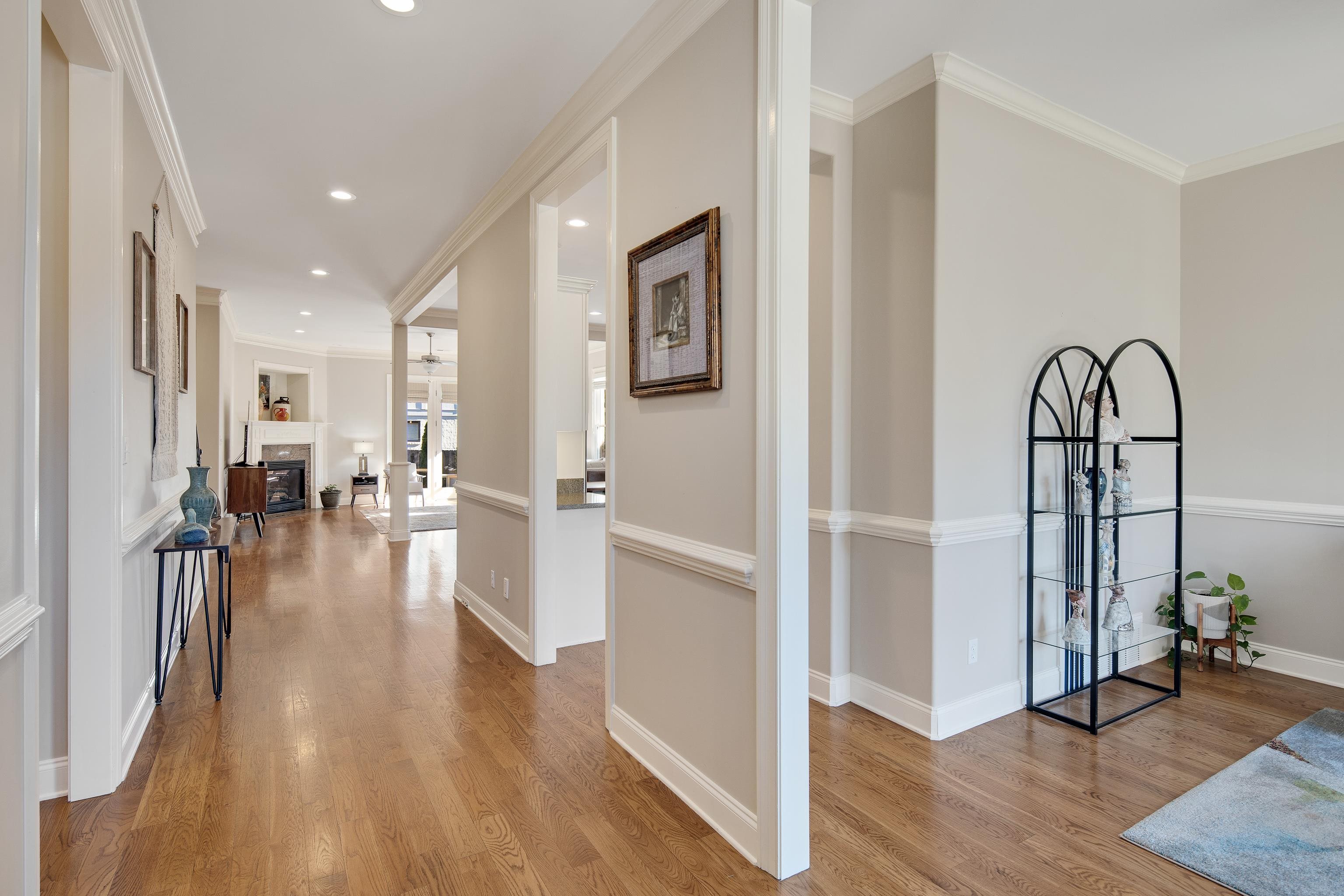 Hallway with decorative columns, crown molding, and light wood-type flooring