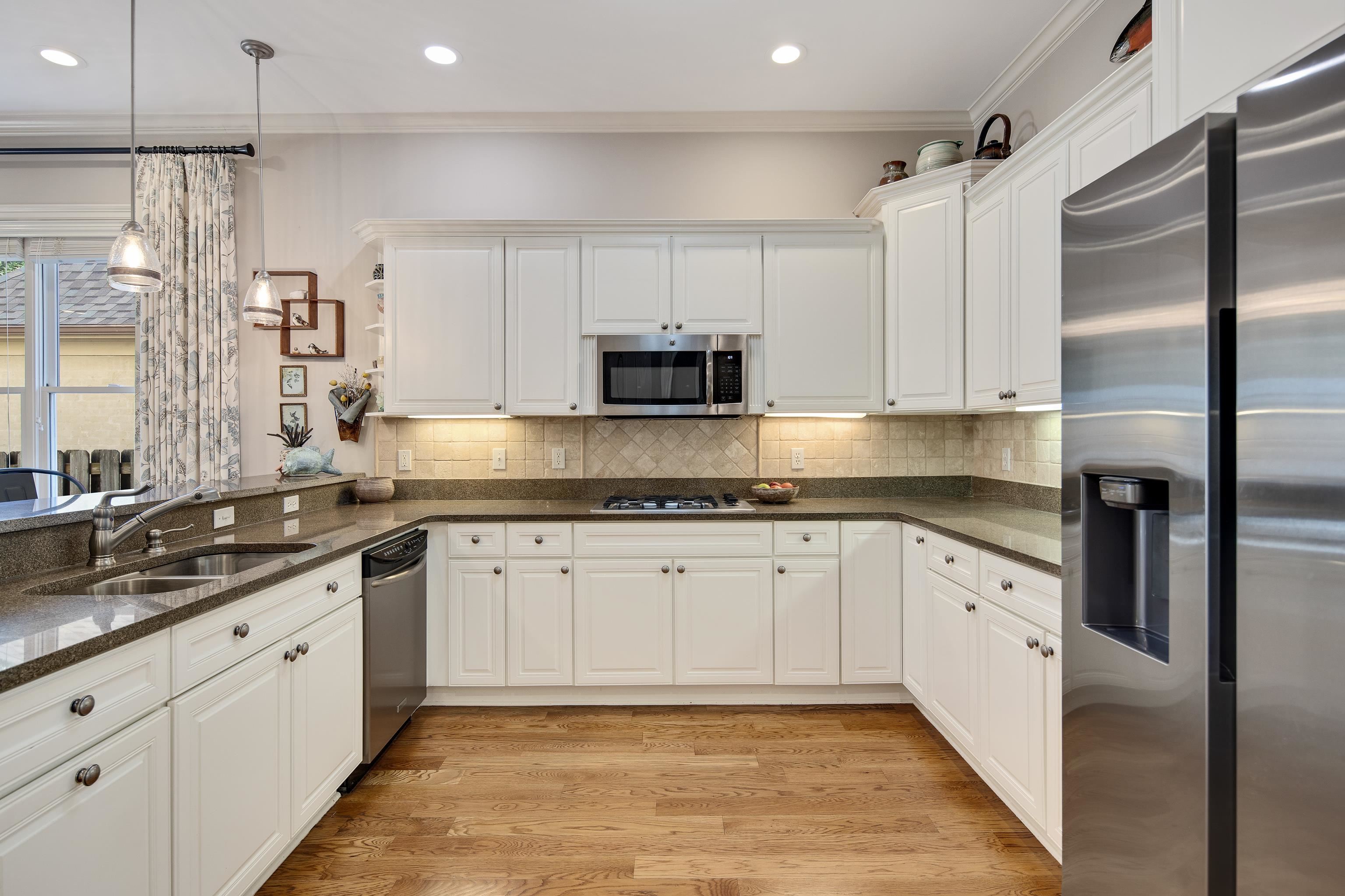 Kitchen featuring pendant lighting, white cabinets, sink, light wood-type flooring, and appliances with stainless steel finishes