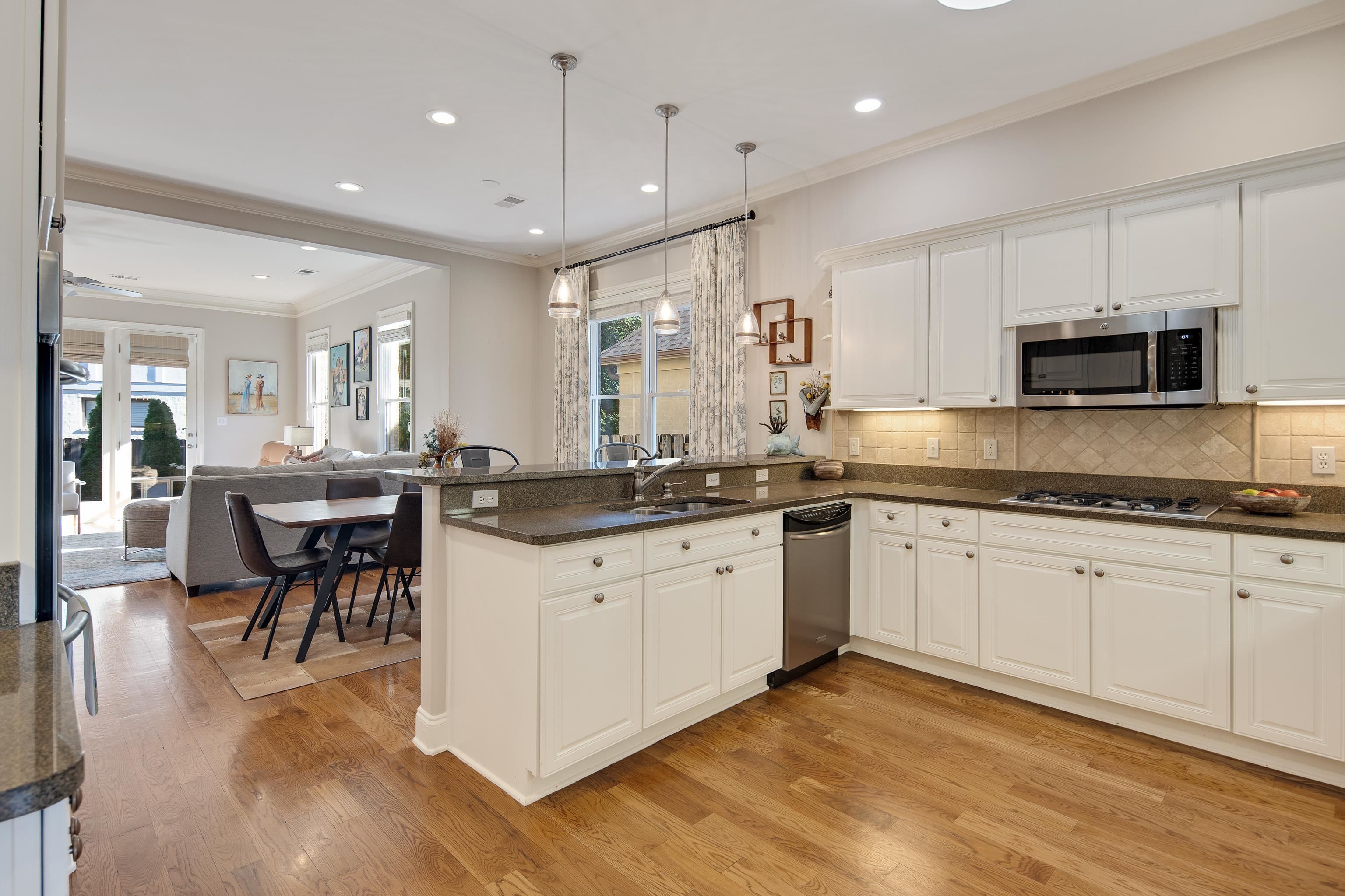 Kitchen with kitchen peninsula, a healthy amount of sunlight, stainless steel appliances, and decorative light fixtures