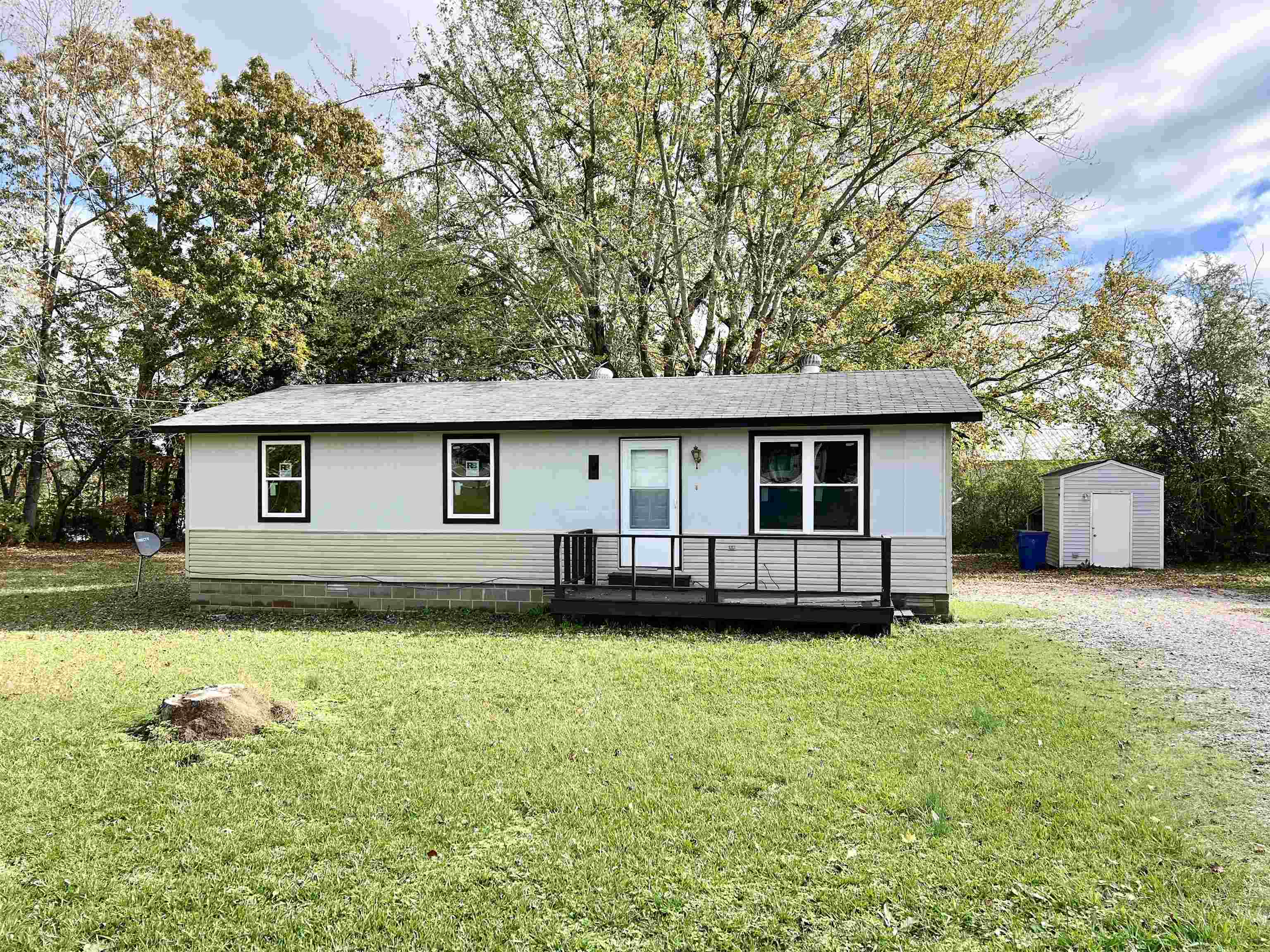 View of front of home with a front yard and a storage unit