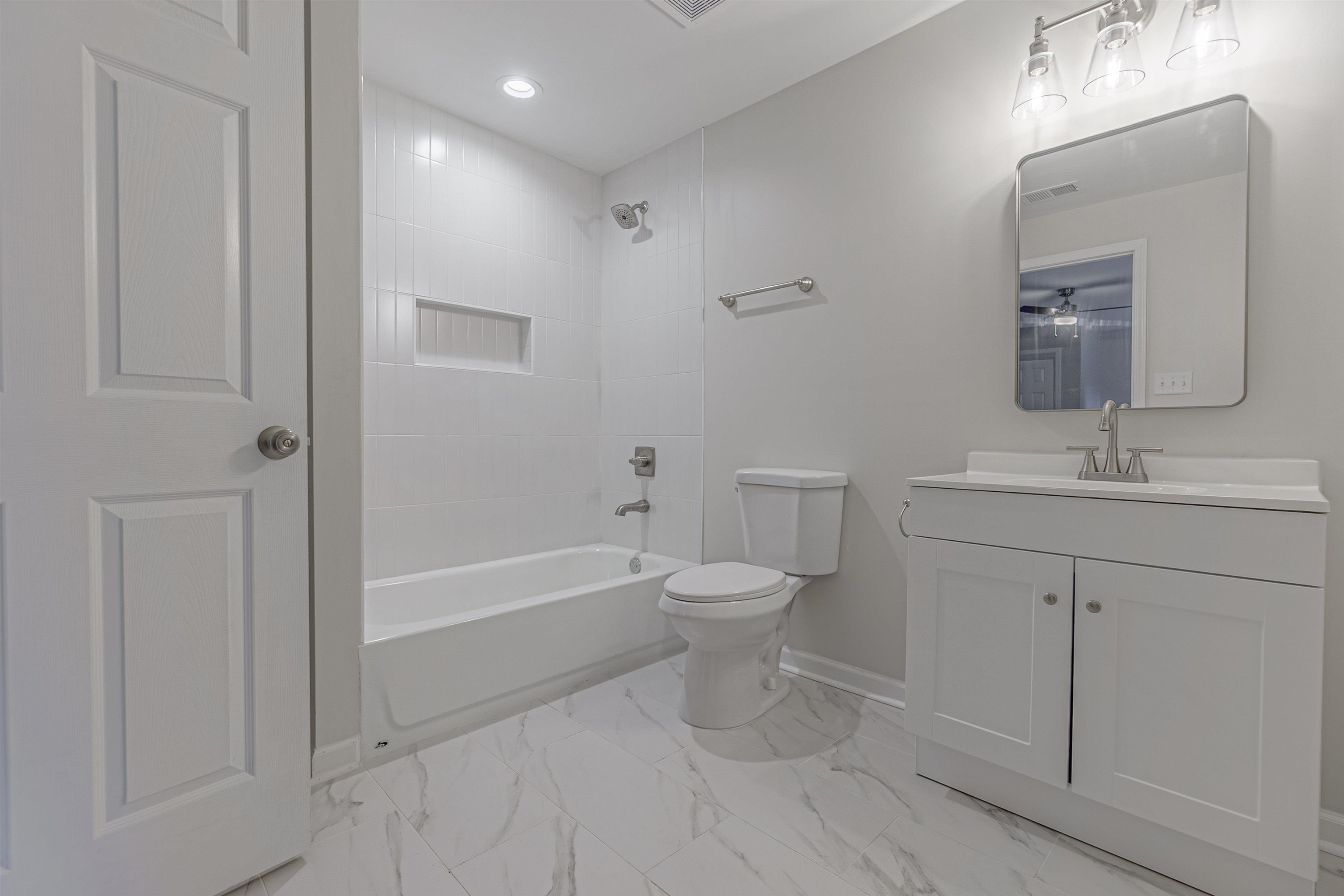 Full bathroom featuring vanity, tiled shower / bath combo, and toilet