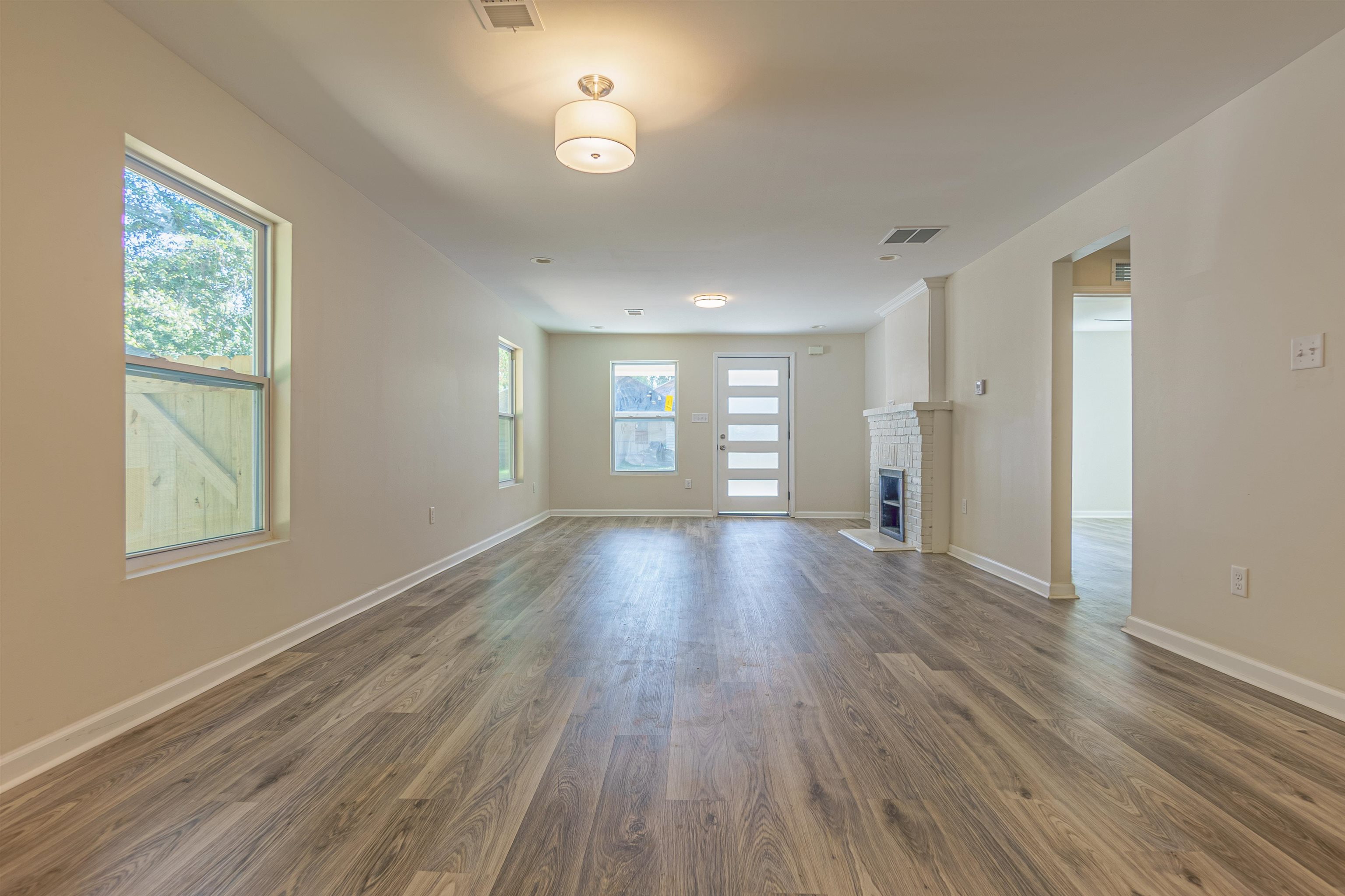 Unfurnished living room with a fireplace, a wealth of natural light, and dark hardwood / wood-style flooring