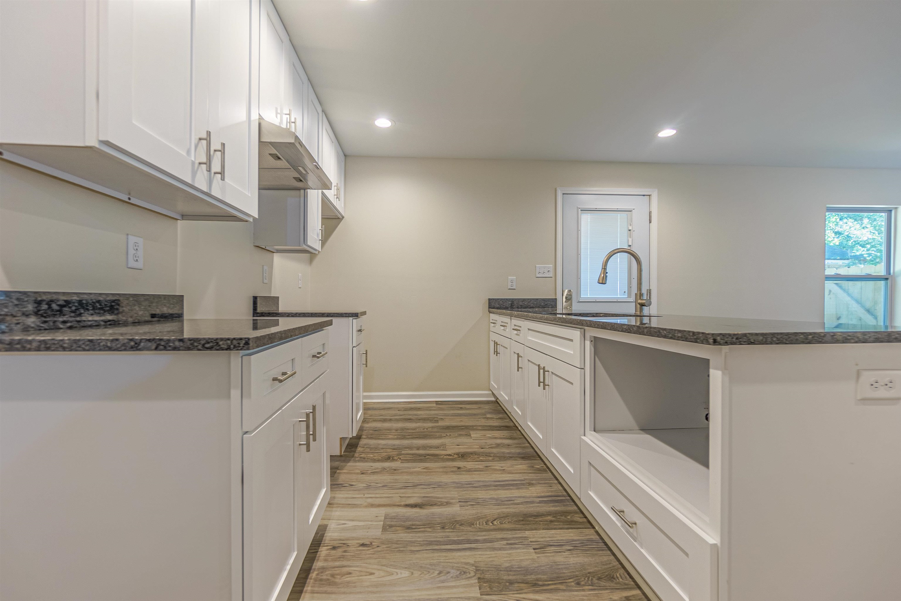 Kitchen featuring kitchen peninsula, hardwood / wood-style floors, white cabinets, and range hood