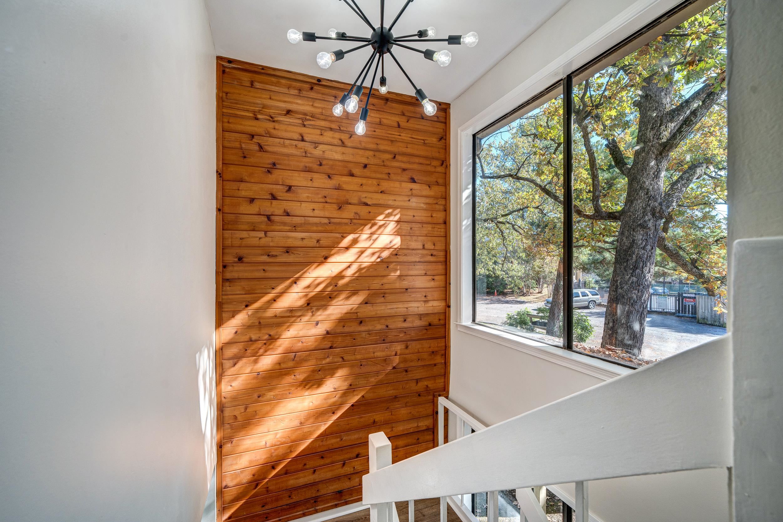 Stairway featuring a chandelier, a wealth of natural light, and wood walls