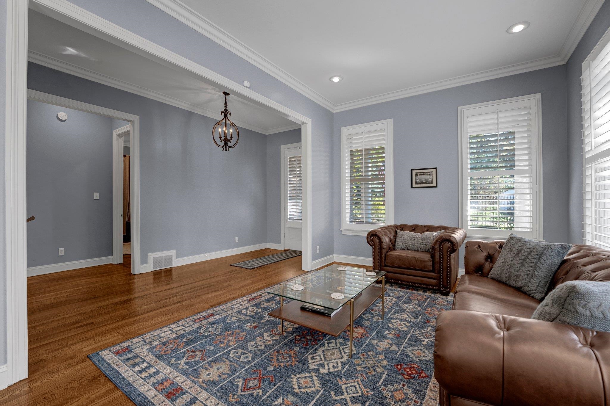 Living room featuring a chandelier, crown molding, and dark wood-type flooring