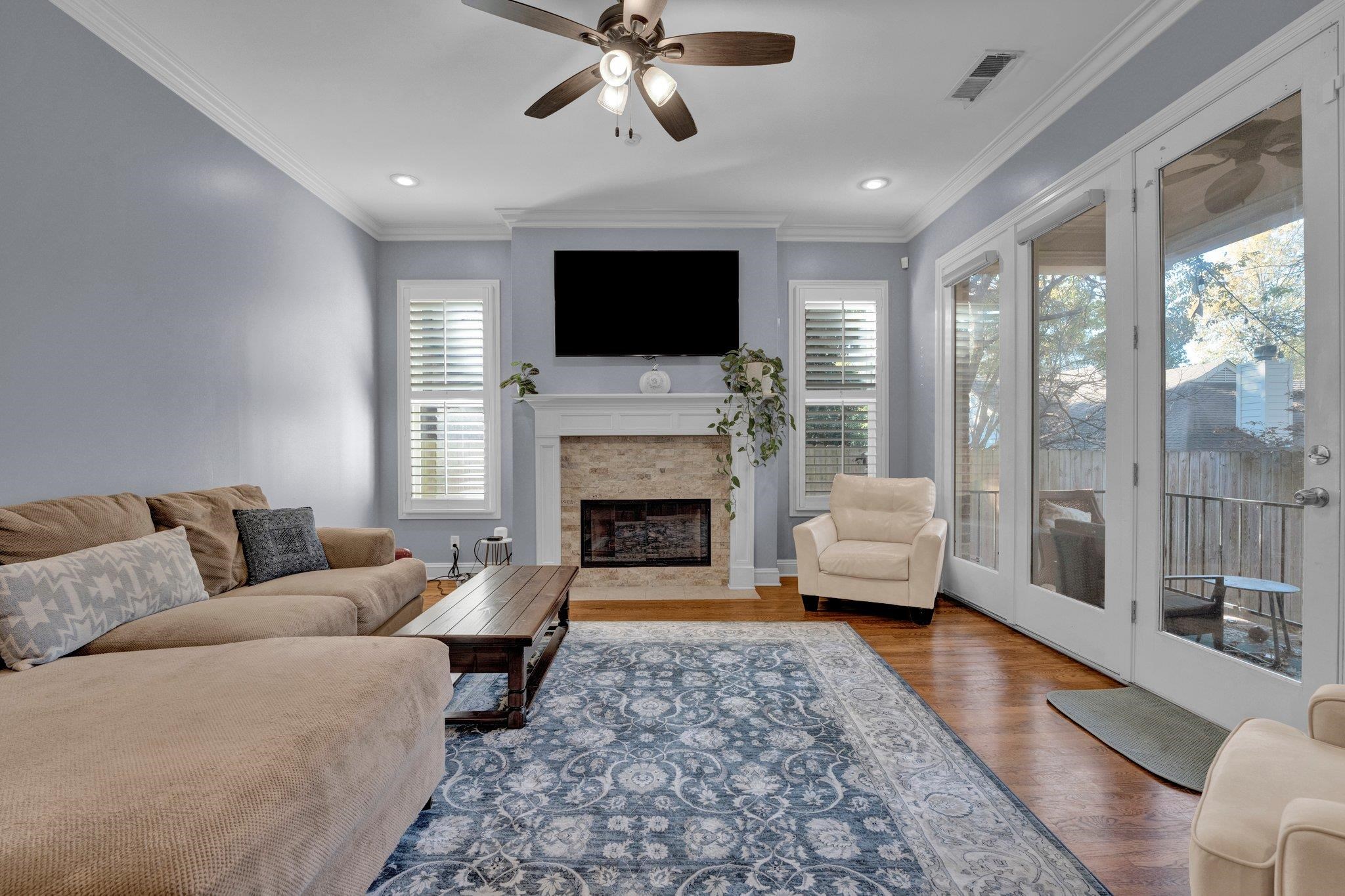 Living room with hardwood / wood-style floors, ceiling fan, and ornamental molding