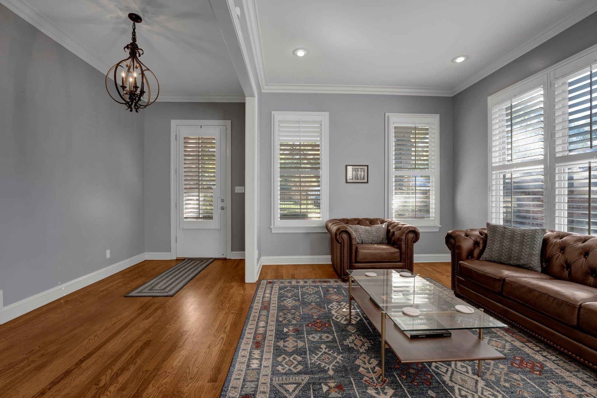 Living room with hardwood / wood-style floors, a notable chandelier, and crown molding