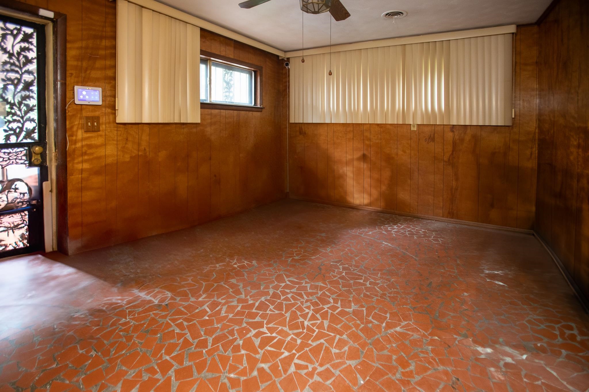 Empty room with ceiling fan and wood walls