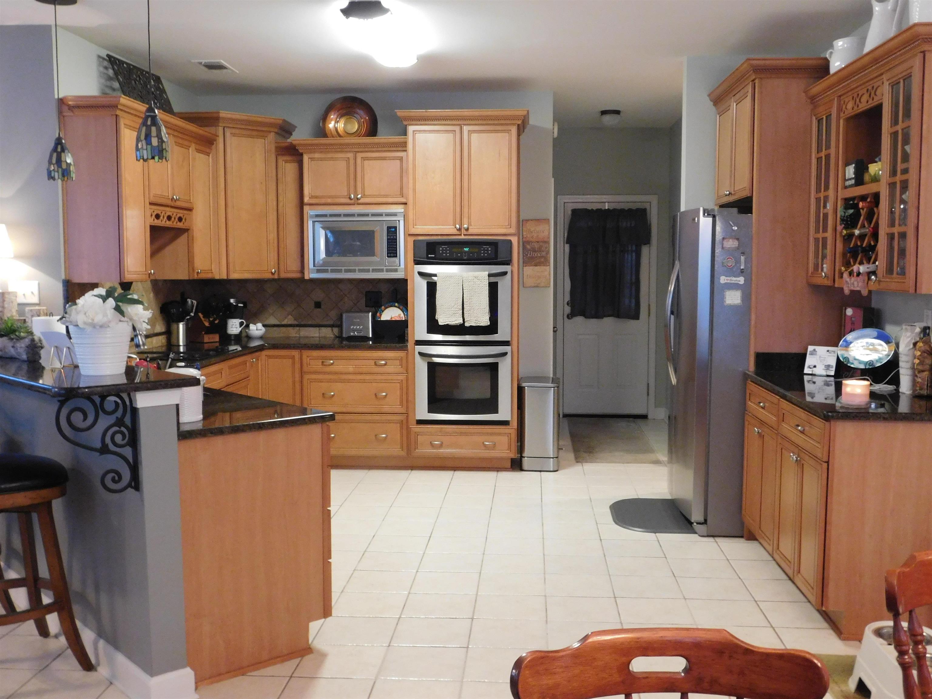 Kitchen with pendant lighting, a breakfast bar area, decorative backsplash, light tile patterned flooring, and stainless steel appliances