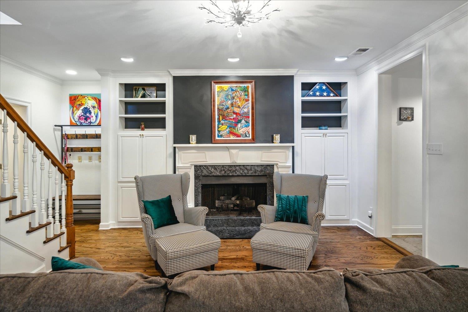 Living room with hardwood / wood-style floors, built in features, a premium fireplace, and ornamental molding