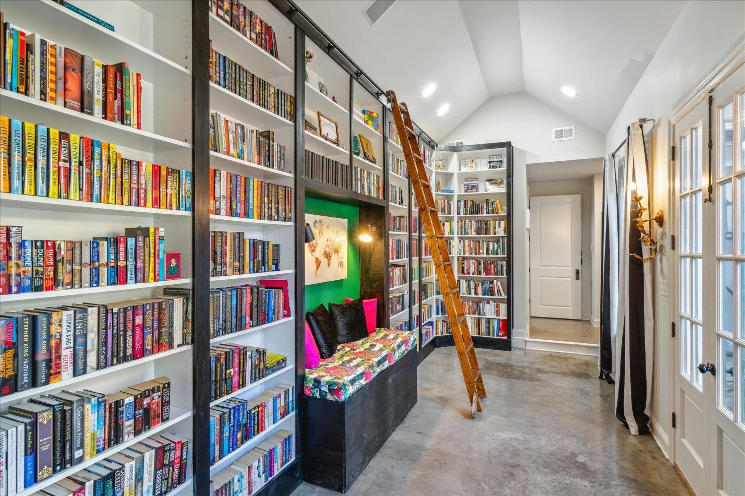 Sitting room with lofted ceiling, a wealth of natural light, and concrete flooring