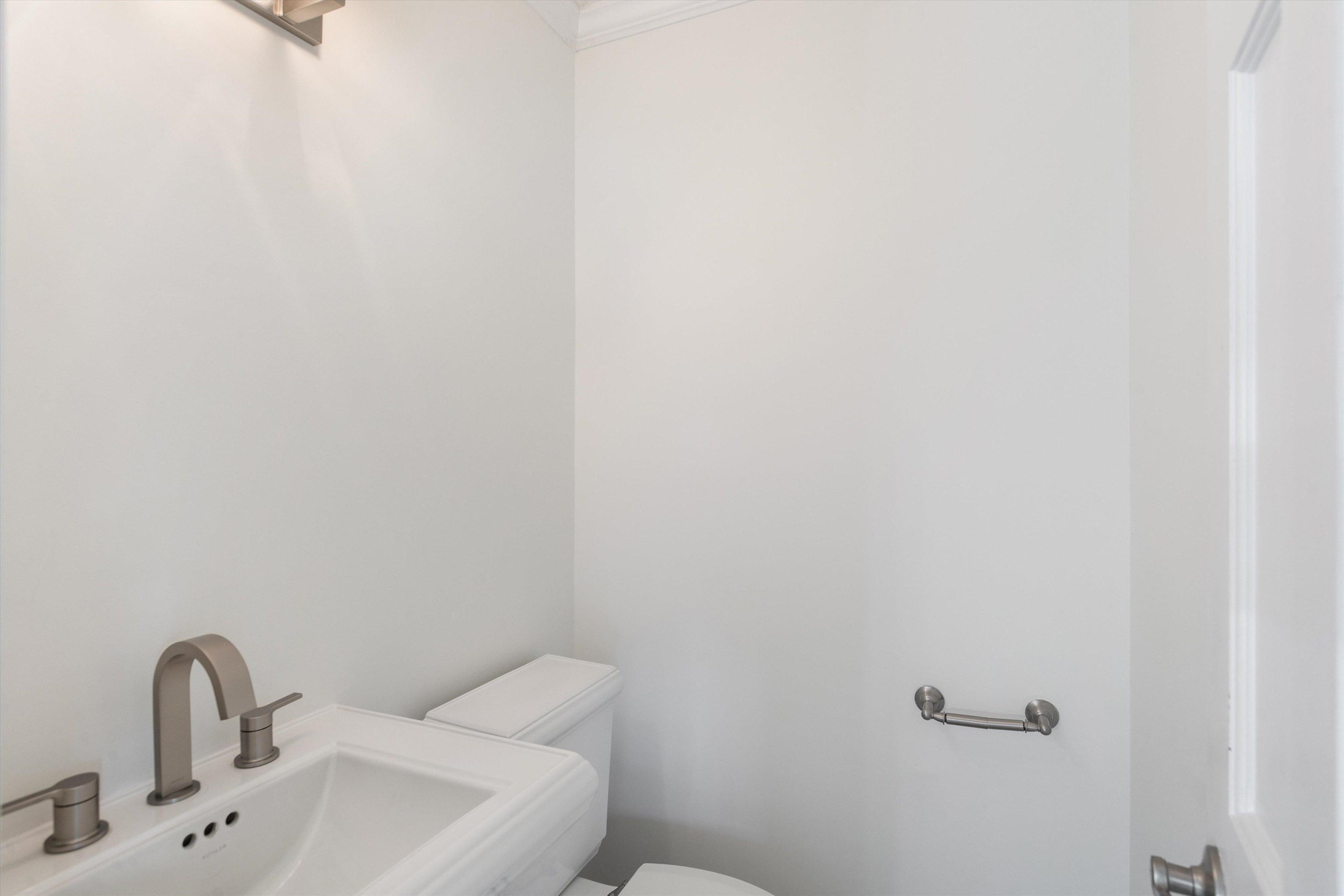 Bathroom with toilet, crown molding, and sink