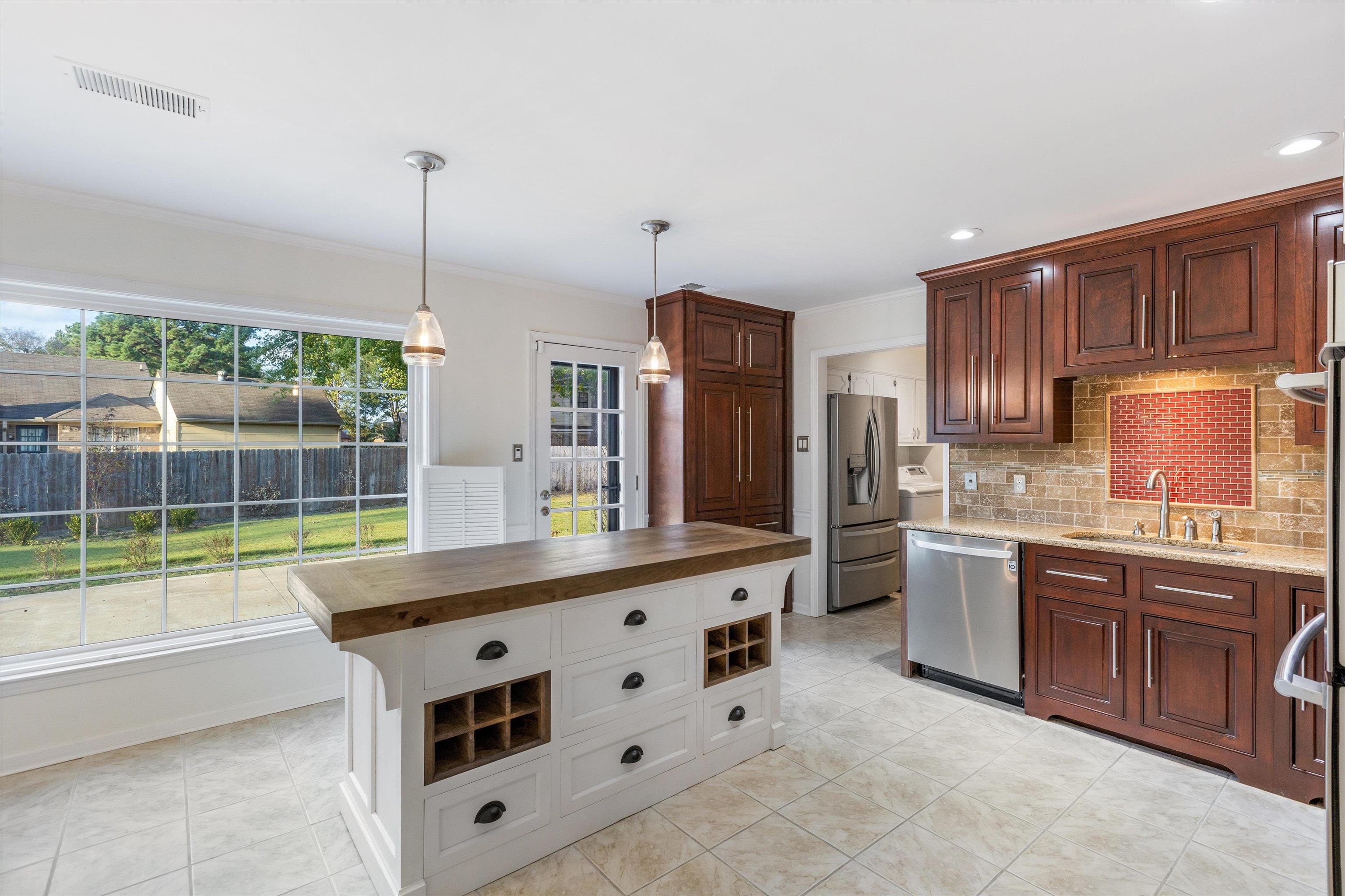 Kitchen featuring pendant lighting, wood counters, backsplash, sink, and appliances with stainless steel finishes