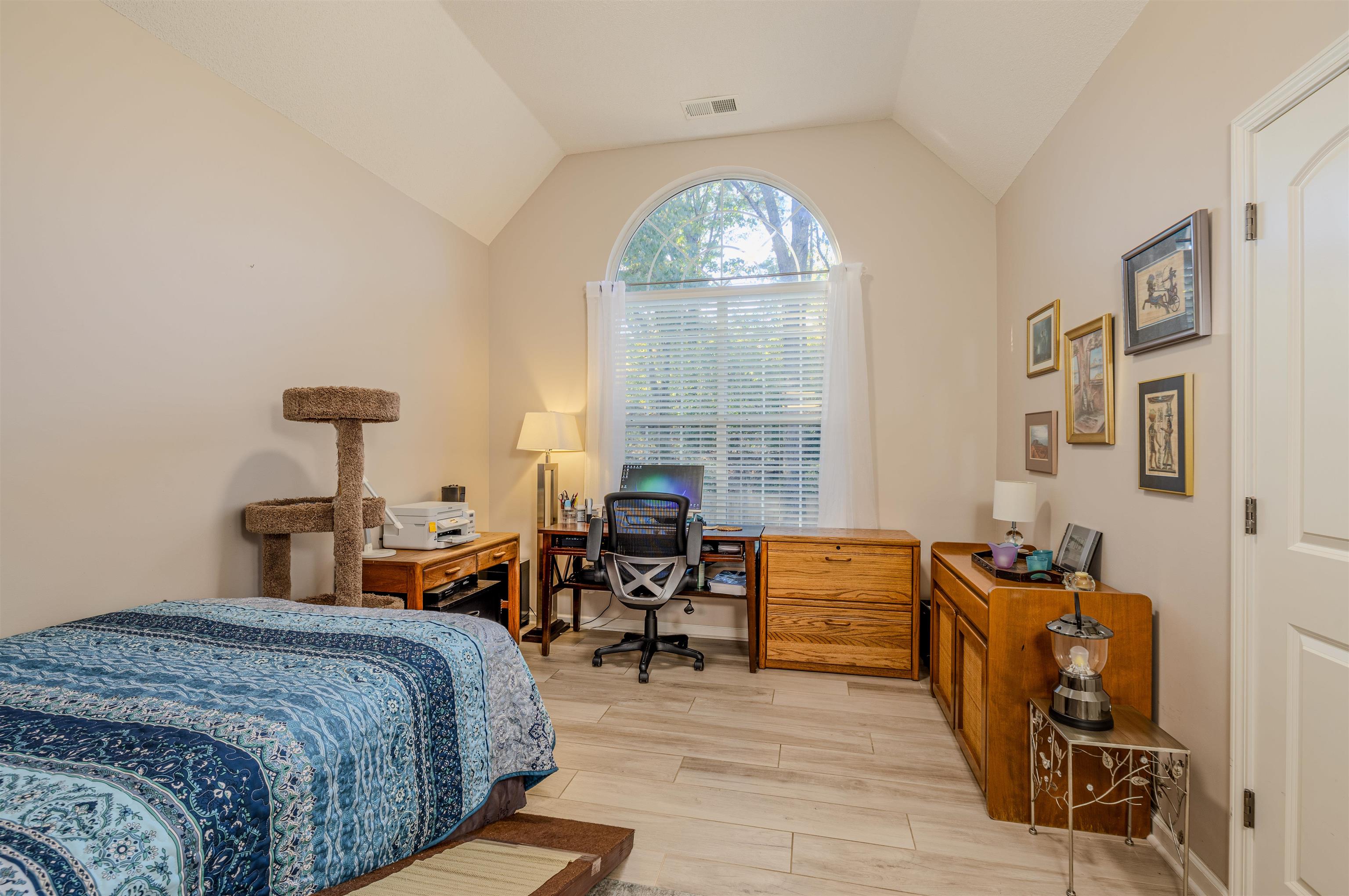 Bedroom with light hardwood / wood-style floors and vaulted ceiling