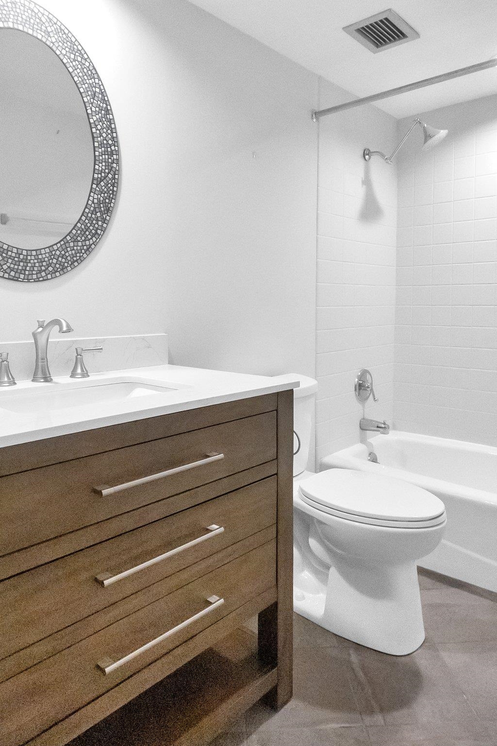 Full bathroom with vanity, tiled shower / bath combo, and toilet