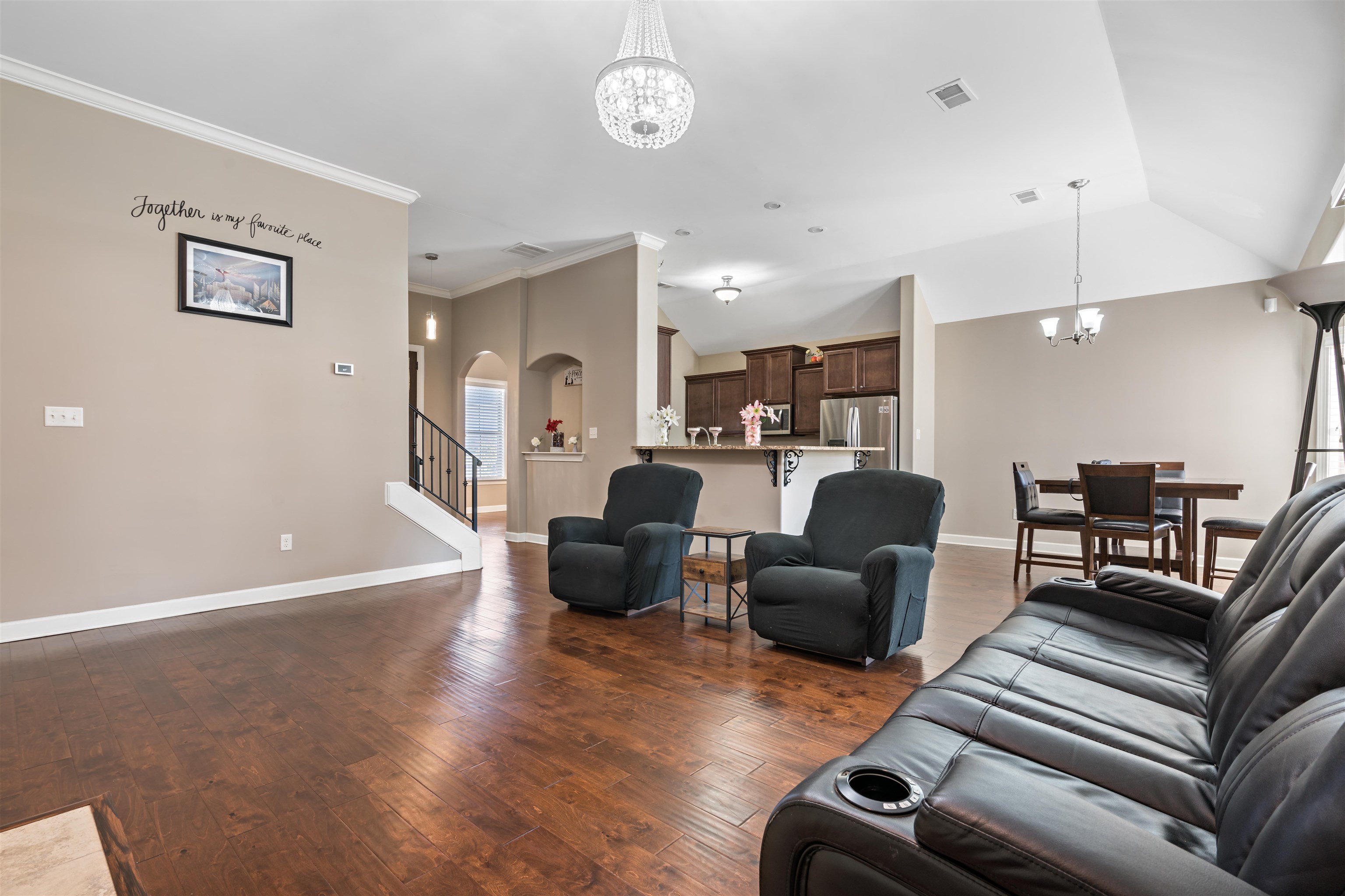 Living room featuring crown molding, dark hardwood / wood-style flooring, vaulted ceiling, and a notable chandelier