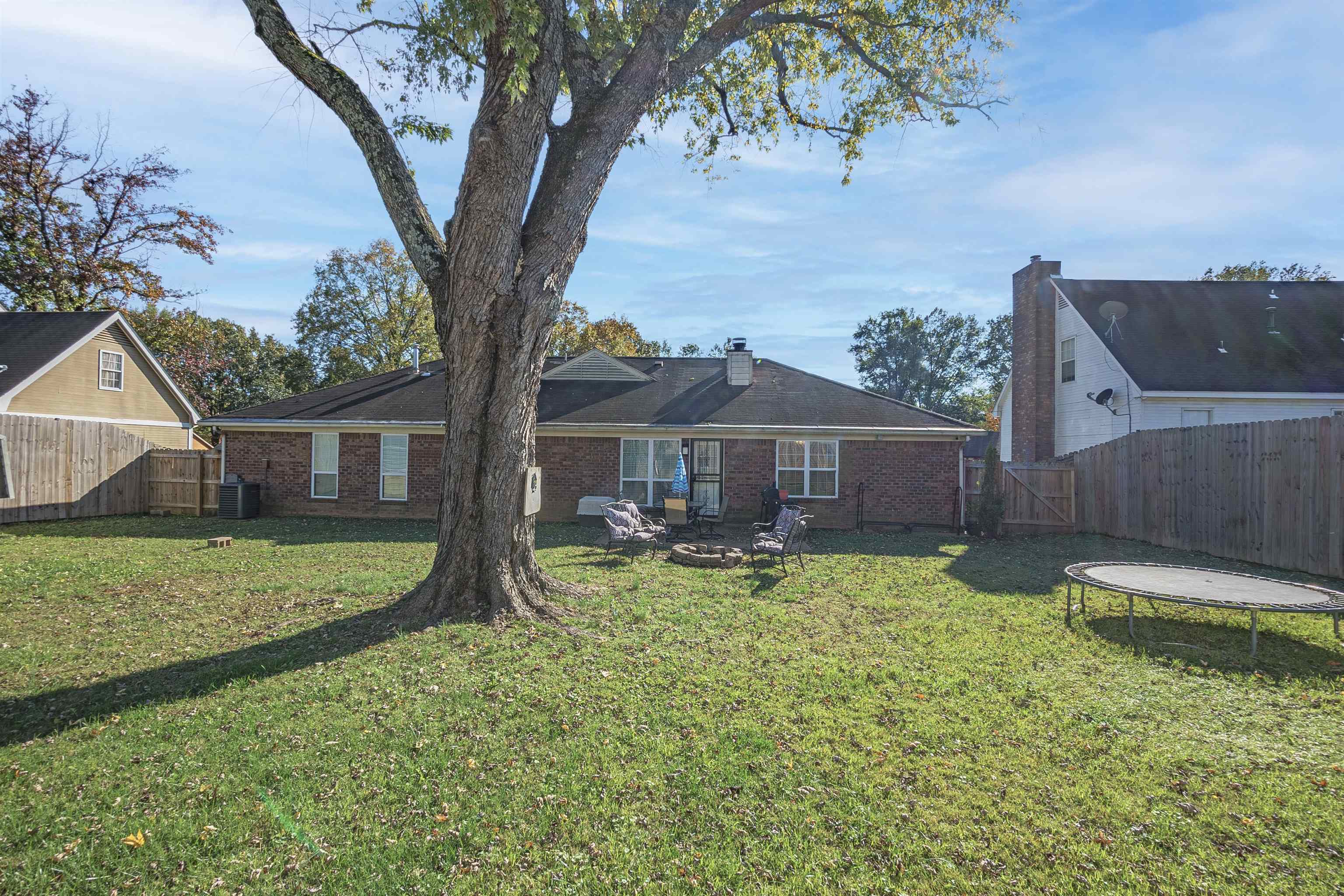 Back of house featuring a fire pit, a trampoline, a yard, and central AC